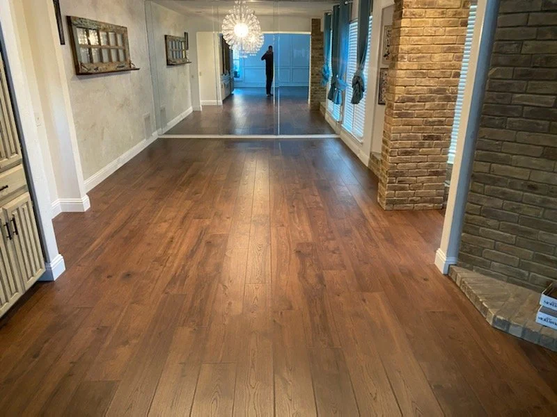Indoor room with wooden flooring, mirrored wall, and exposed brick accents