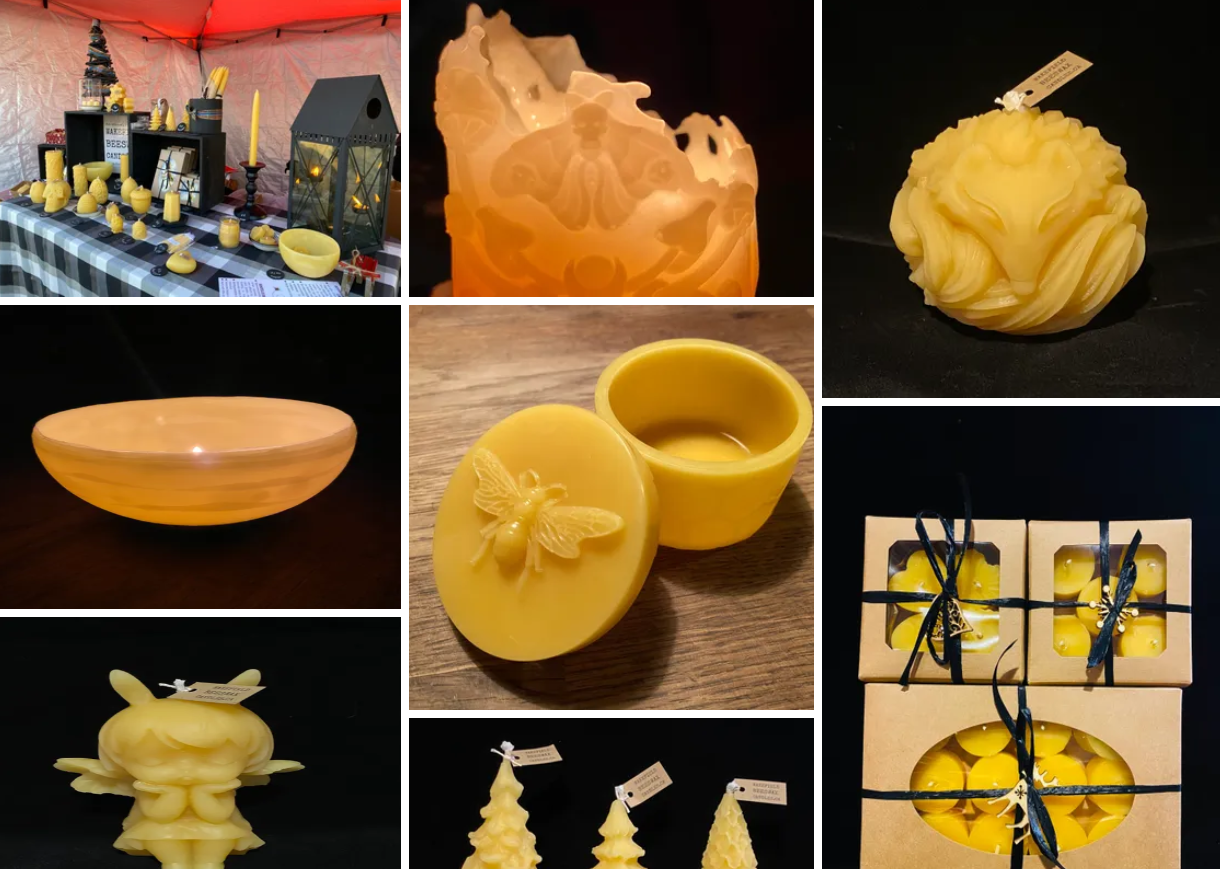 Collection of yellow wax candles and wax figurines, including a church, rabbit, bee, and Christmas trees, displayed at a vendor booth.