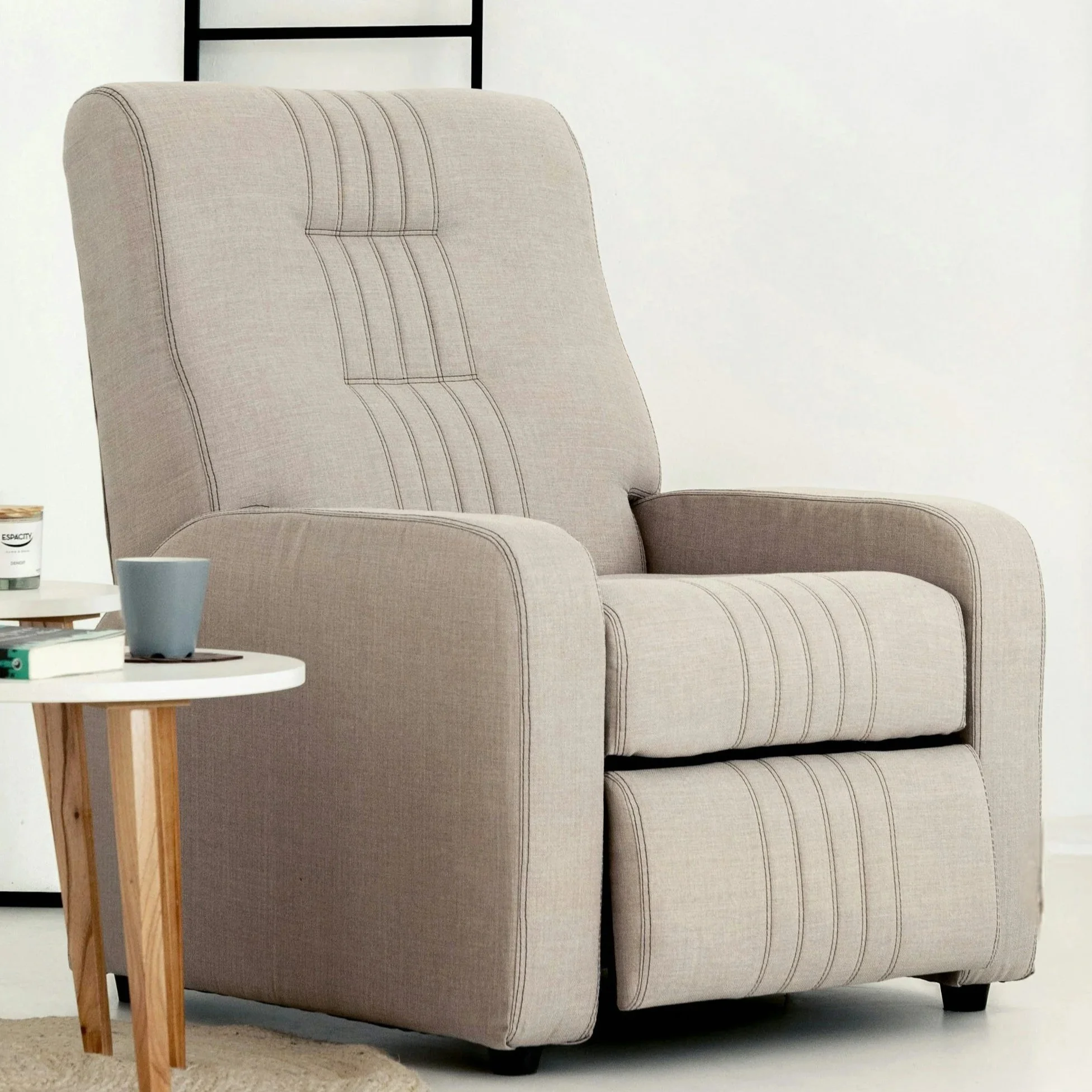 Light beige recliner next to a white coffee table with a book and fresh cup of coffee