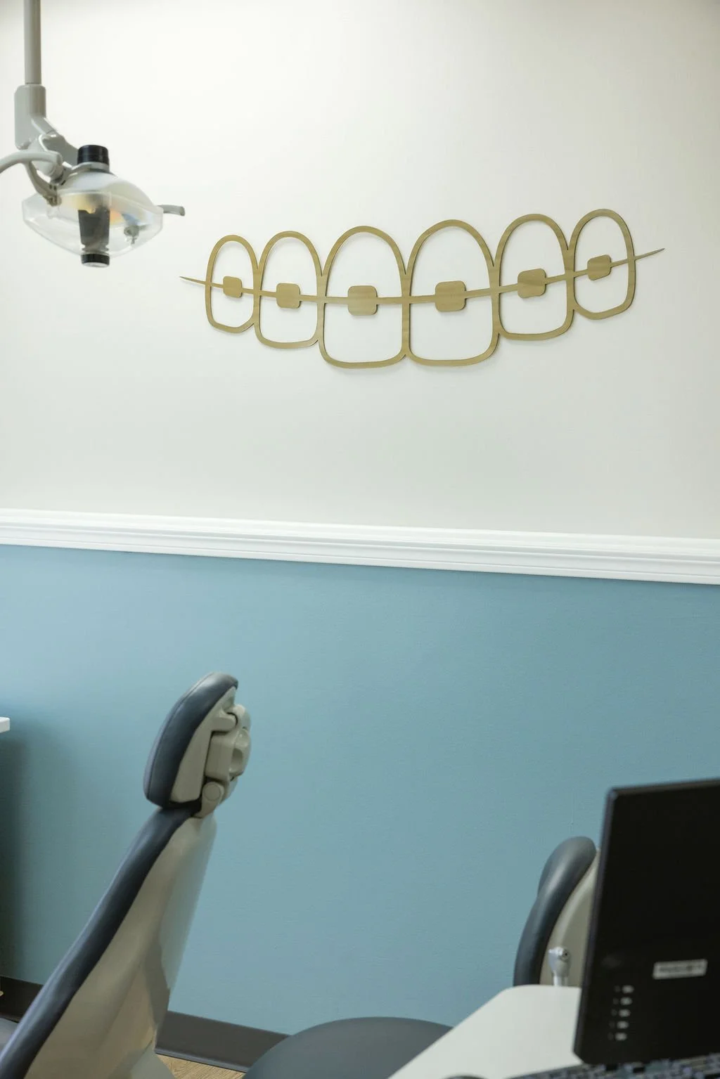 Modern orthodontic office interior with dental chair and braces wall art, reflecting the comfortable patient experience included in treatment