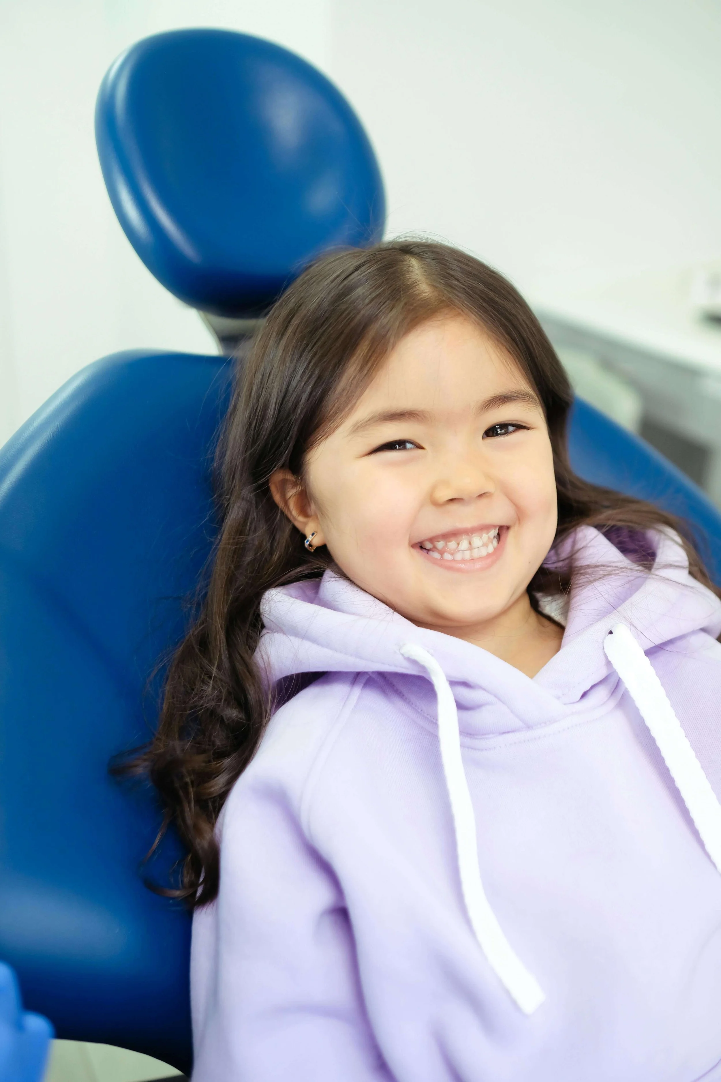 Young child smiling in an orthodontic chair during an early orthodontic visit in Andover KS, showing that treatment can begin as early as age 6 or 7.