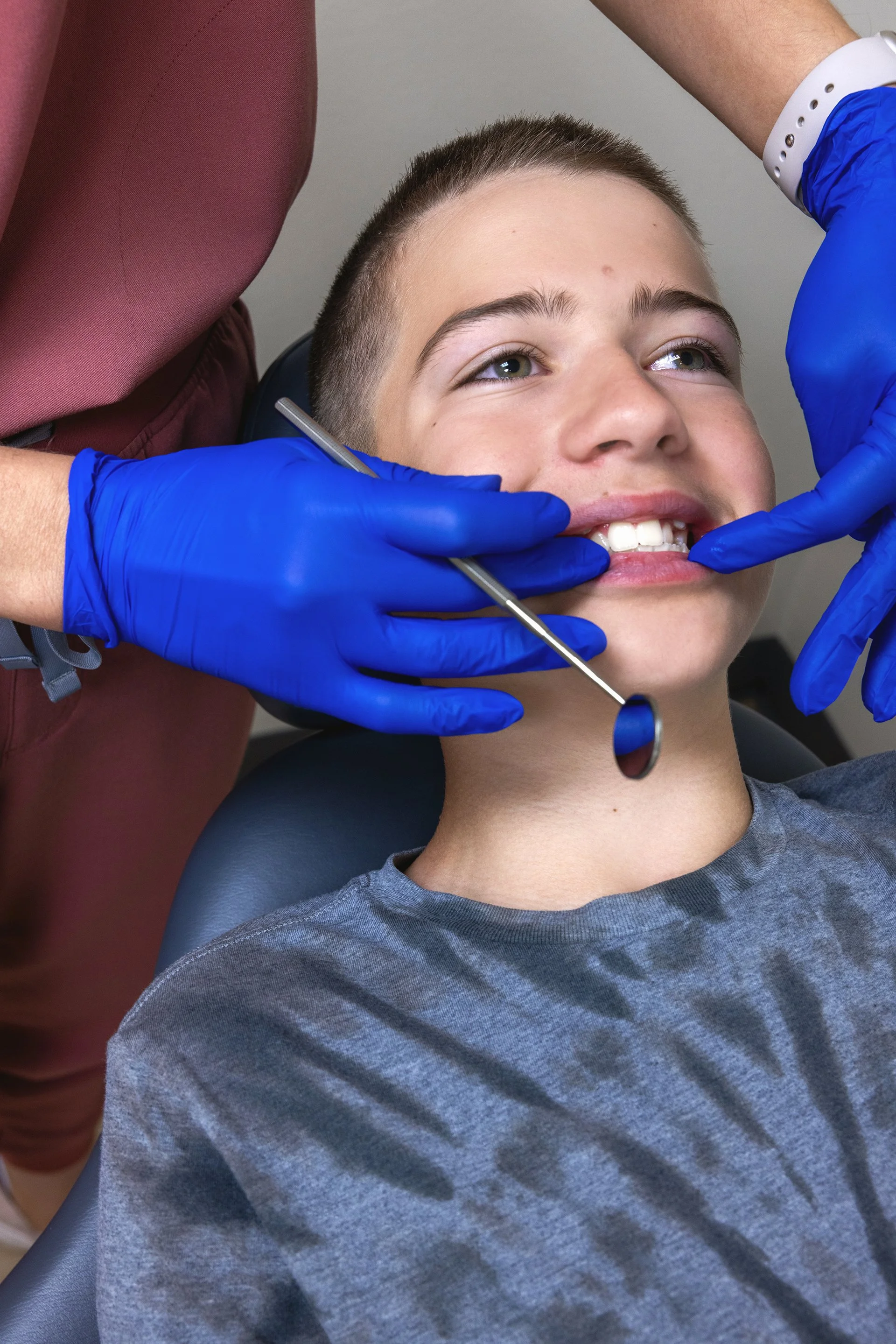 Orthodontist examining a teen patient's bite in person at Sander Orthodontic Arts in Andover, KS
