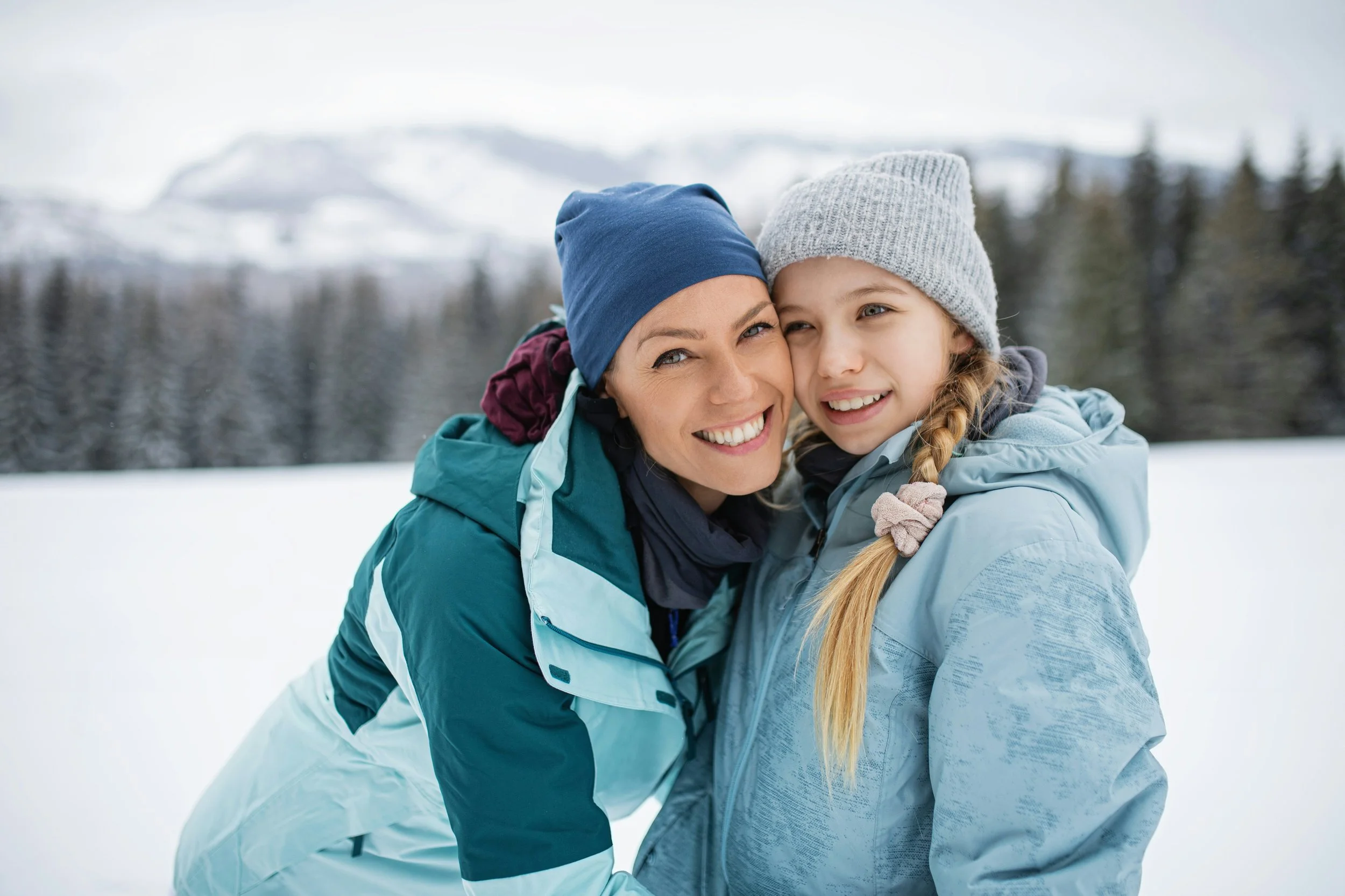 Parent and child smiling together outdoors in winter clothing, illustrating cold-weather reminders for protecting orthodontic retainers and healthy teeth.