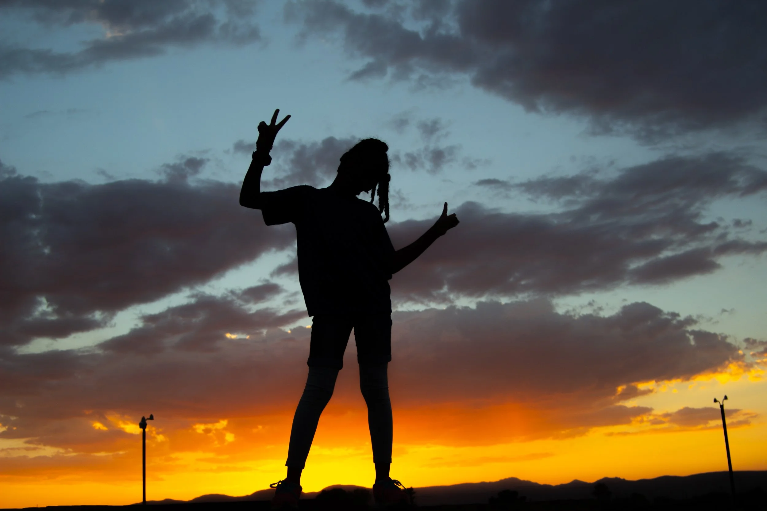 Photo of a young girl giving a peace sign in silhouette