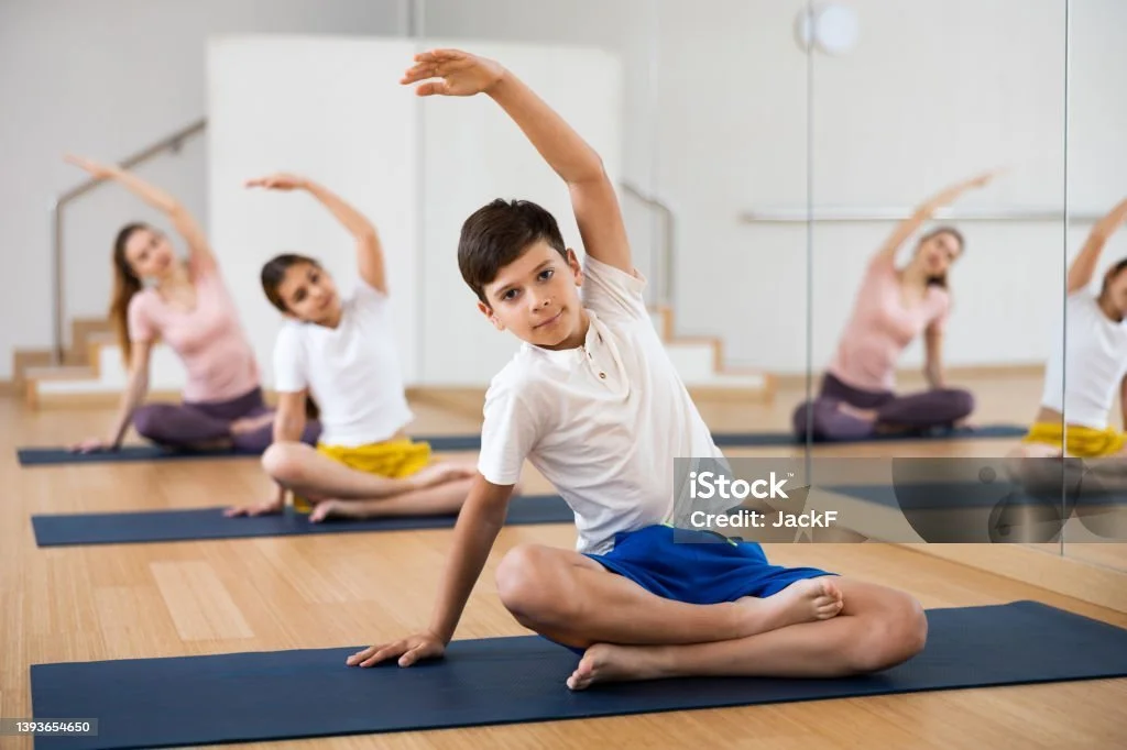 Woman in workout clothes performing a stretch on a Pilates reformer in a studio, surrounded by indoor plants and mirrors.