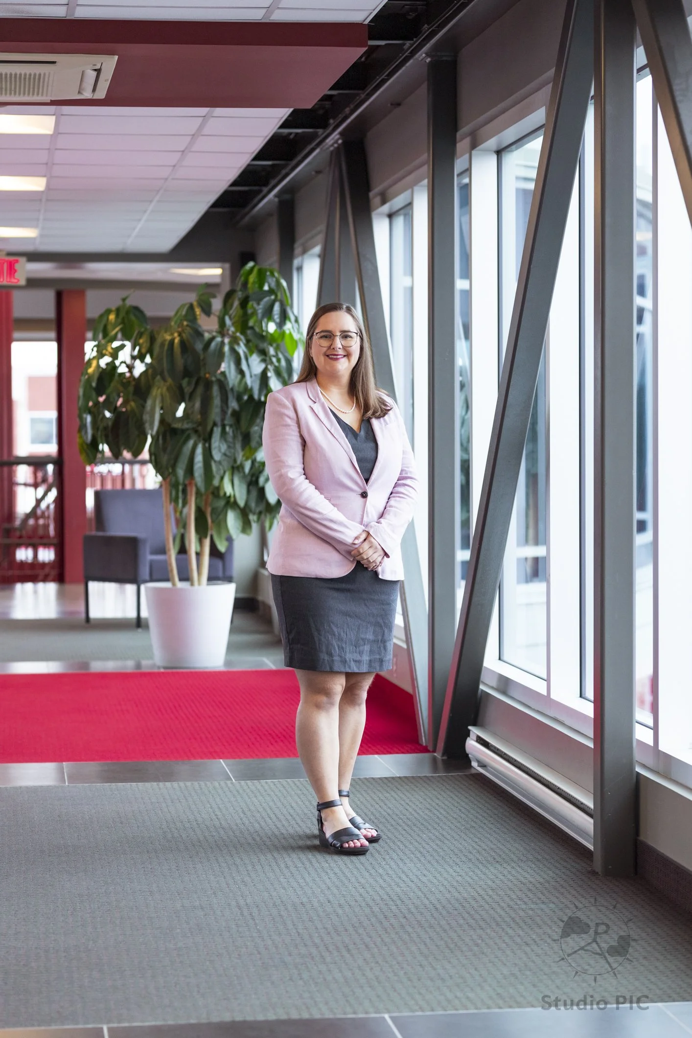 Photo de portrait corporatif d'une jeune femme sur la Passerelle de LaScène Lebourgneuf; portant une robe grise avec un veston rose.