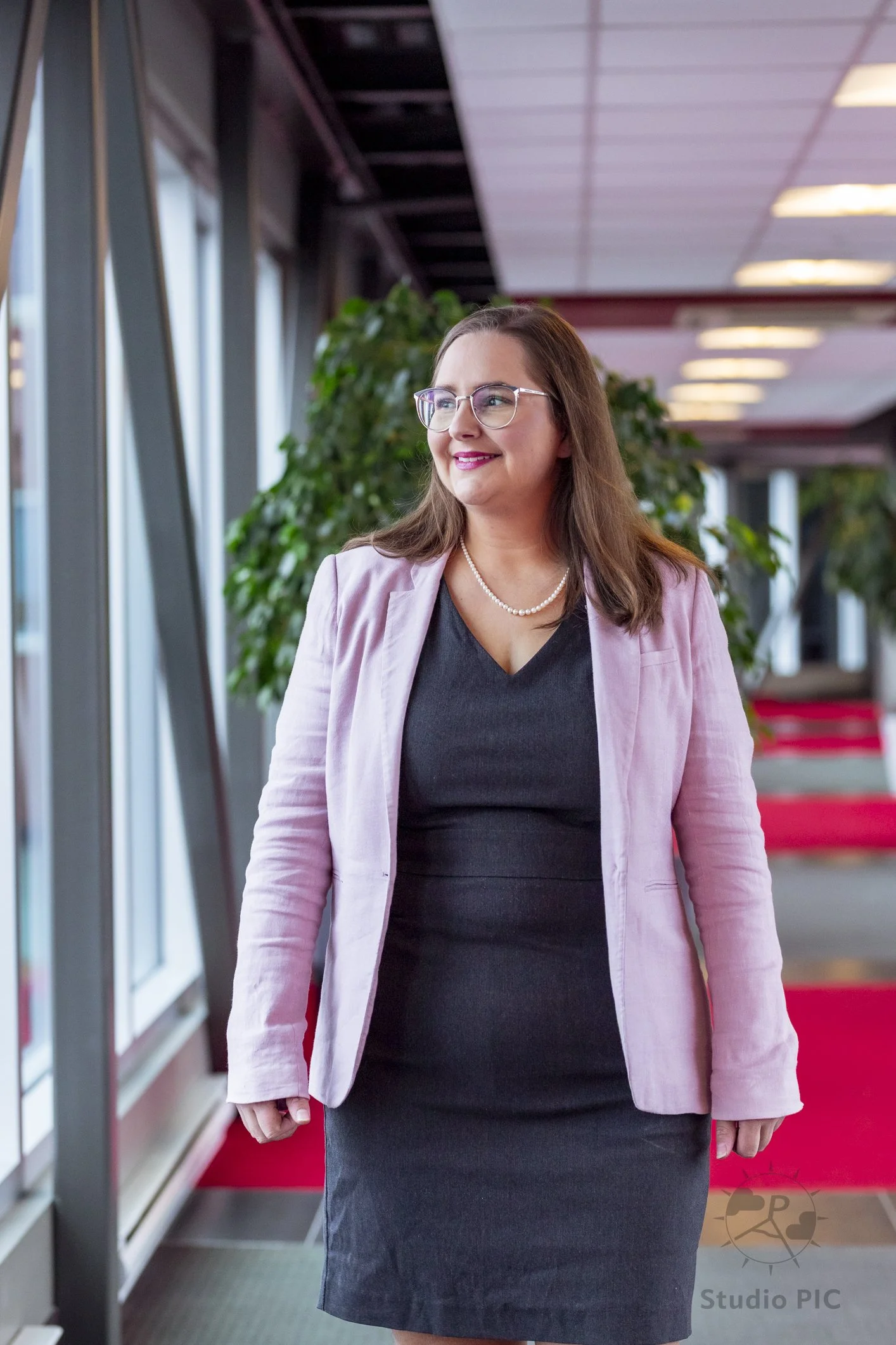 Photo de portrait corporatif d'une femme portant une robe grise et un veston rose sur la passerelle de LaScène Lebourgneuf.
