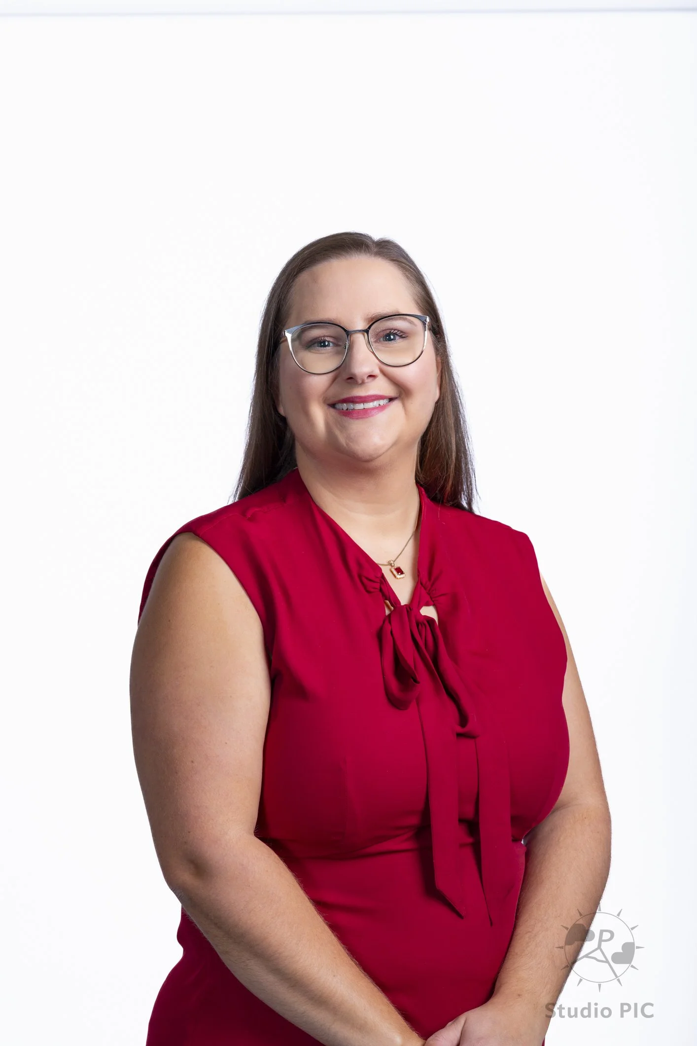 Photo de portrait corporatif en studio d'une jeune femme dans une robe rouge avec un pendentif de l'entreprise Primerica