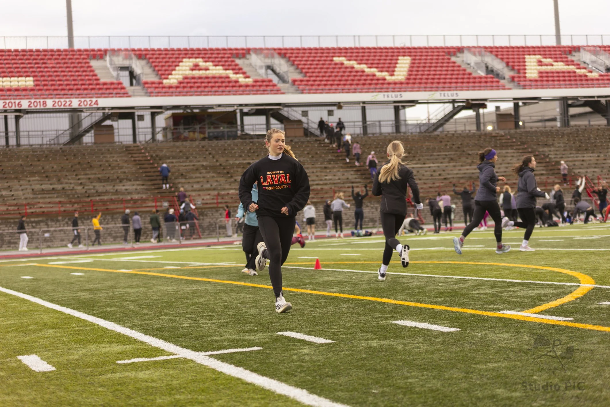 Photo d'un événement à l'Université Laval; nous y voyons une participante courir sur le terrain de football de l'université.