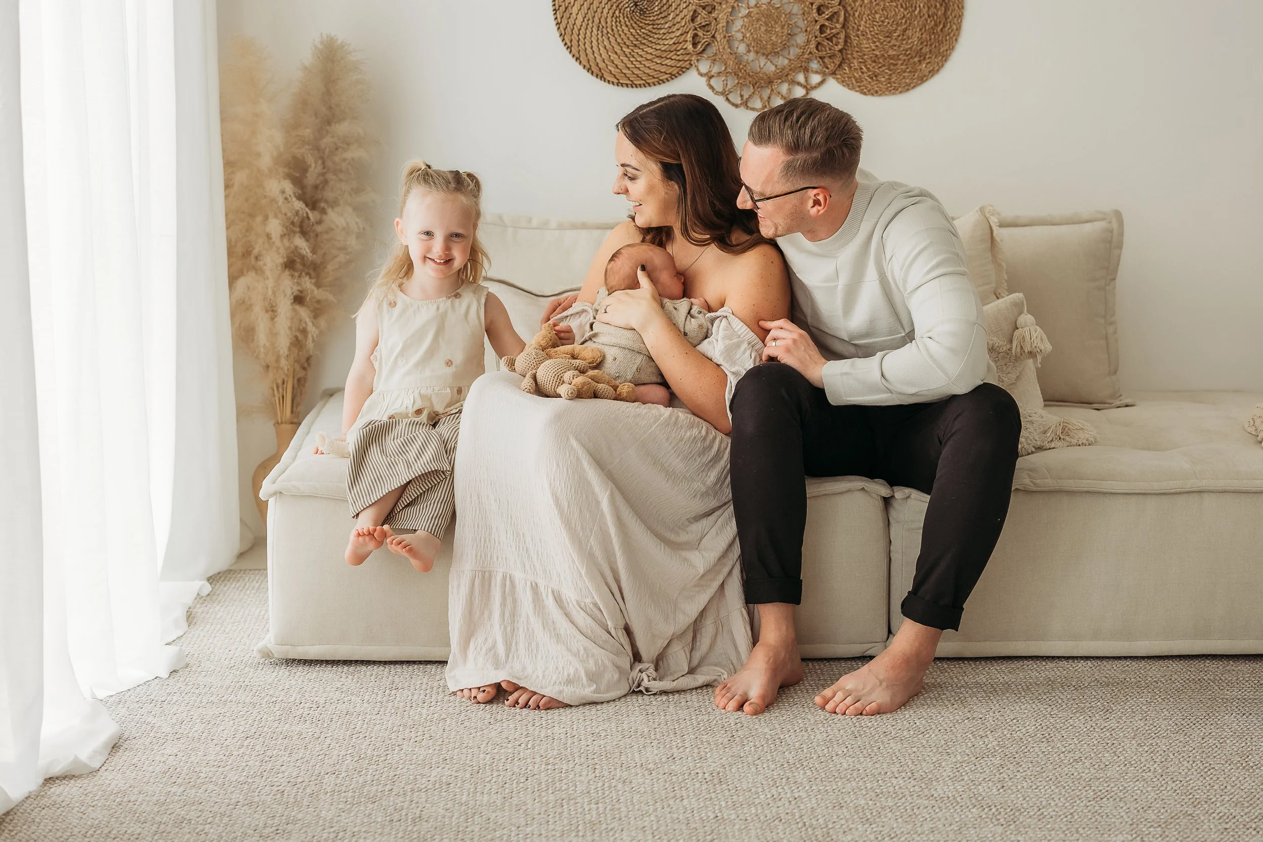 Mum dad big sister and Newborn baby on sofa