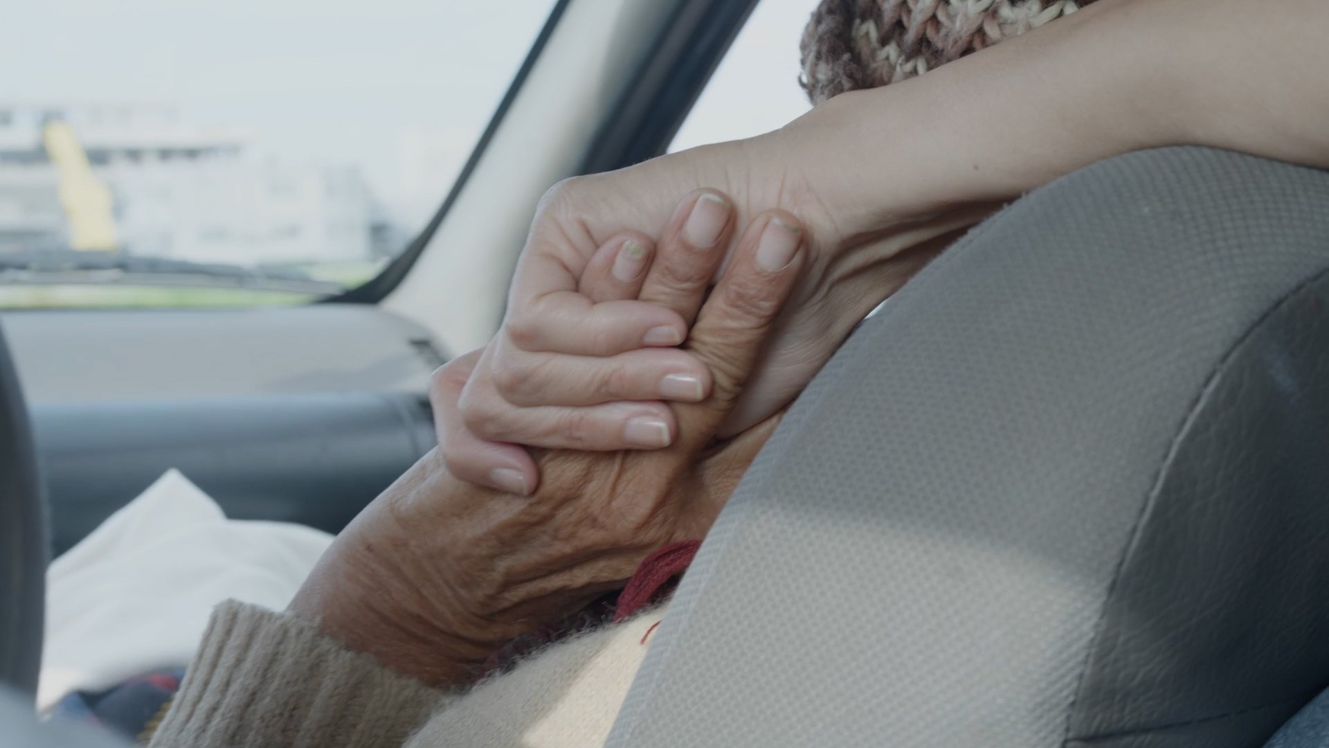 La Higuera. Dos personas tomándose de las manos dentro de un automóvil.