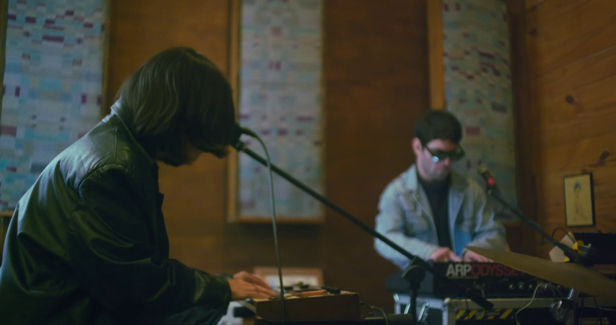 Ino Guridi y Krishna della Valle en el estudio de Casapueblito 1387 tocando en un estudio, uno con un sintetizador ARP Odyssey y otro con un teclado enfrente de un micrófono.