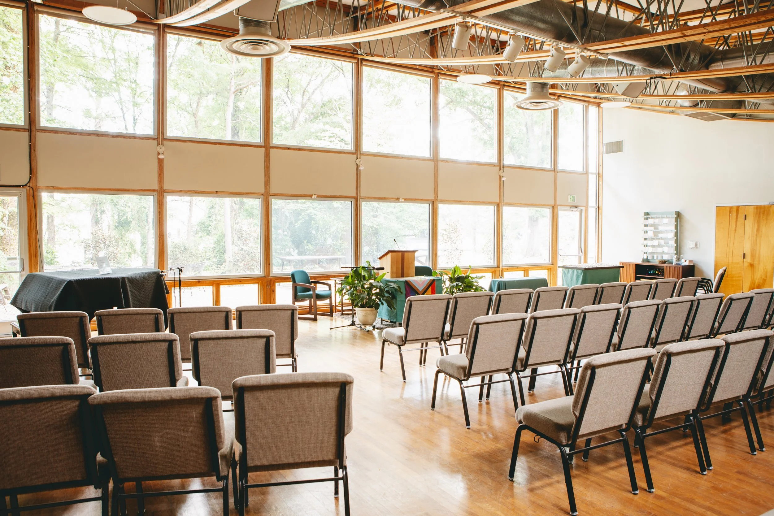 in a light-filled sanctuary, rows of chairs are neatly placed at a gentle angle, facing the altar at the front of the space