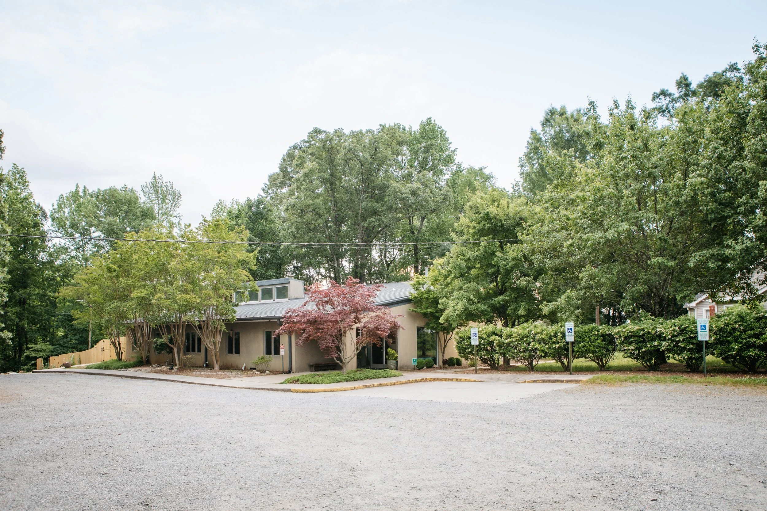 the long, single-story church building of Piedmont Unitarian Universalist peeks through the lush green that surrounds it