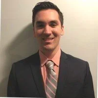 A young man in a suit and tie smiling at the camera.