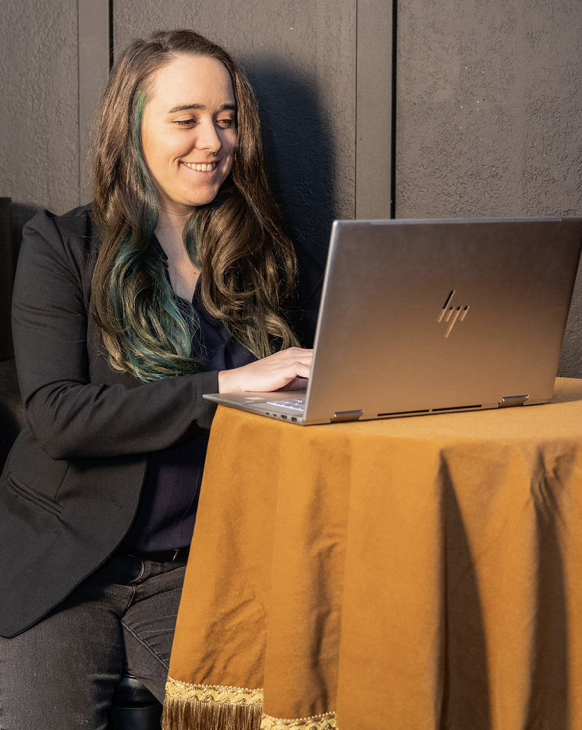 Nikki sits at a laptop with a smile, helping business owners create a website that converts