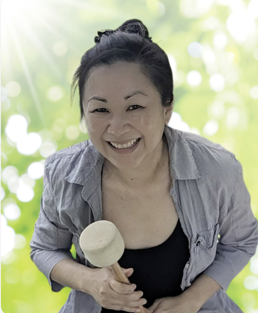 Cinsy smiles, holding a mallet to create a healing sound bath experience