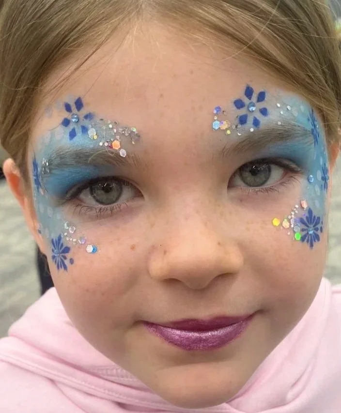 "Winter-themed holly and snowflake face paint design created at a South London christmas party"

