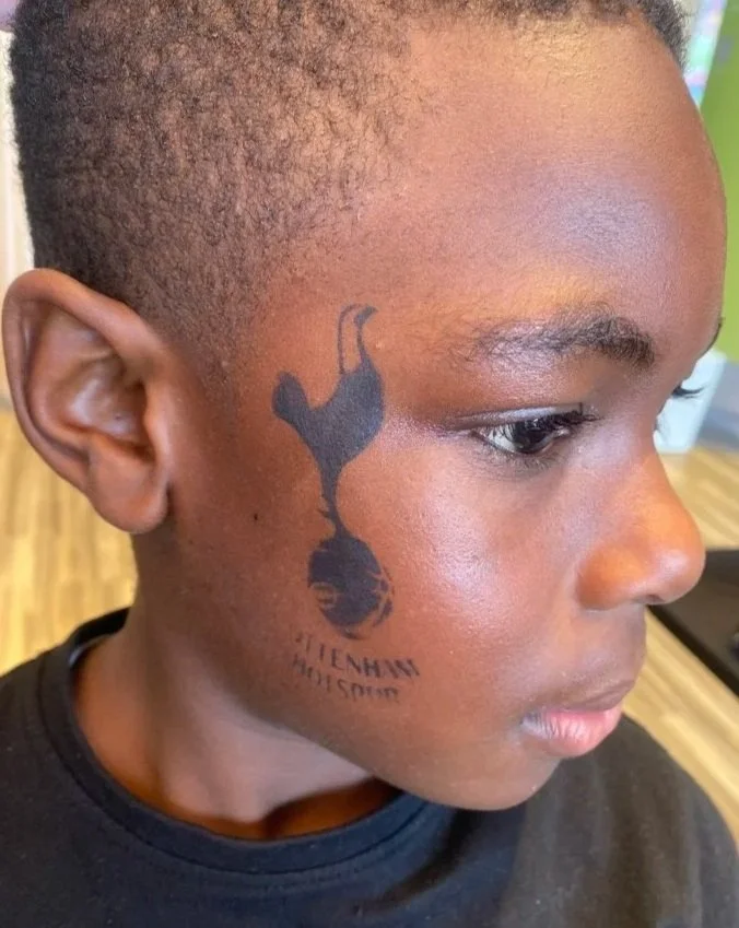 "Professional face painter creating colourful designs for children at a corporate event"