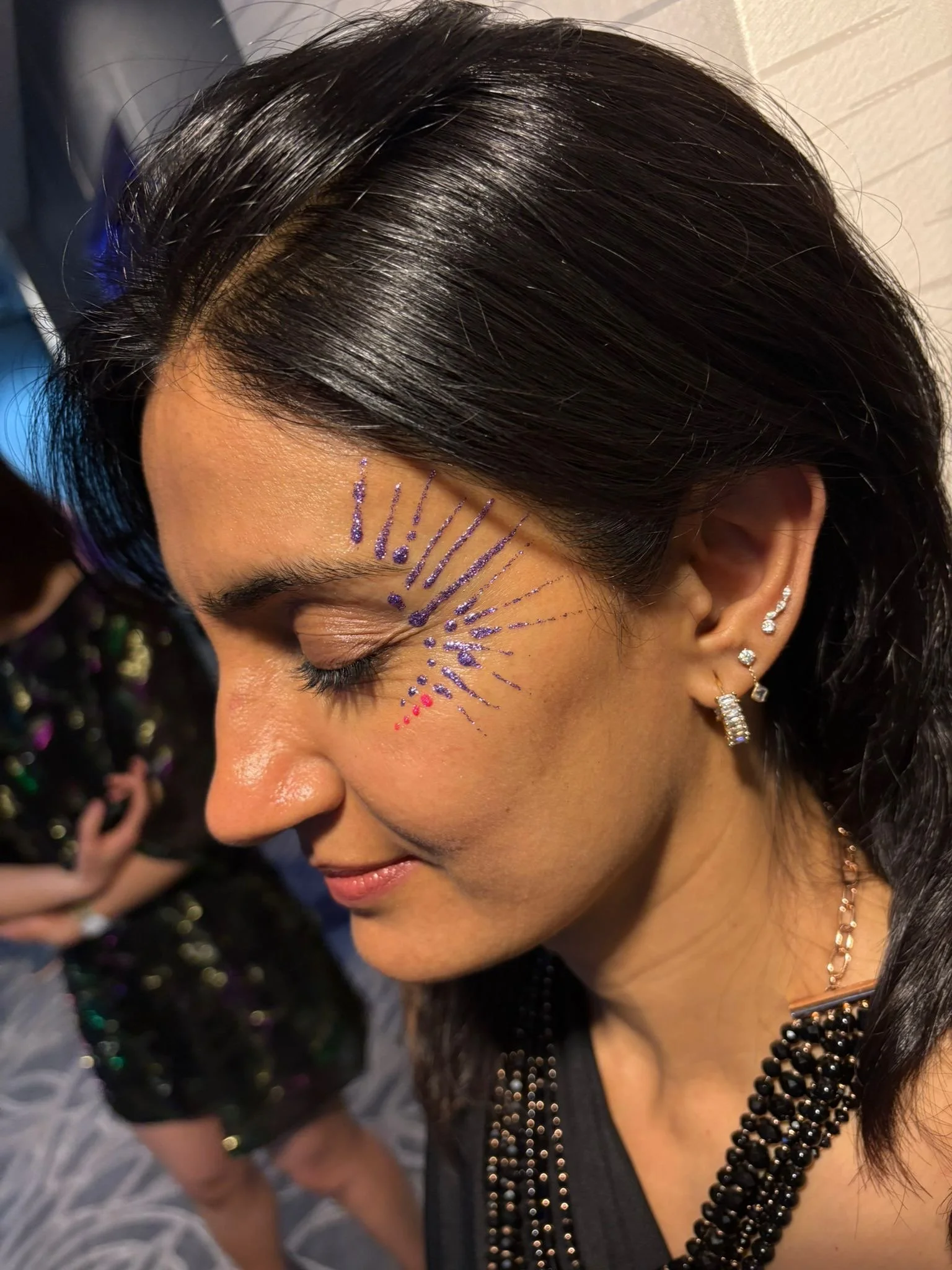 "Professional glitter body art setup with stencils and brushes at a Central London celebration"