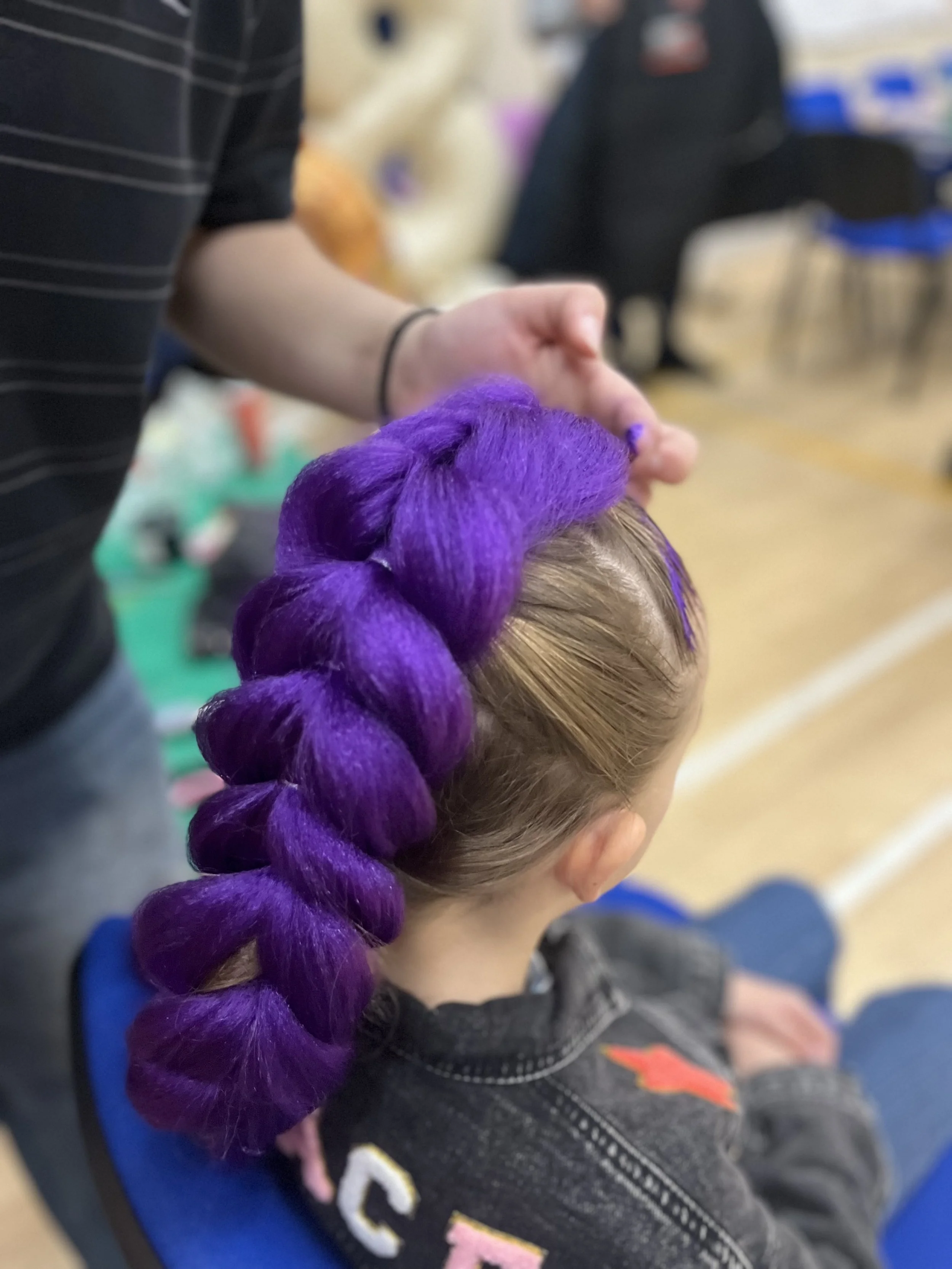 “K‑Pop inspired colourful braids styled for a child at a party in London.”
