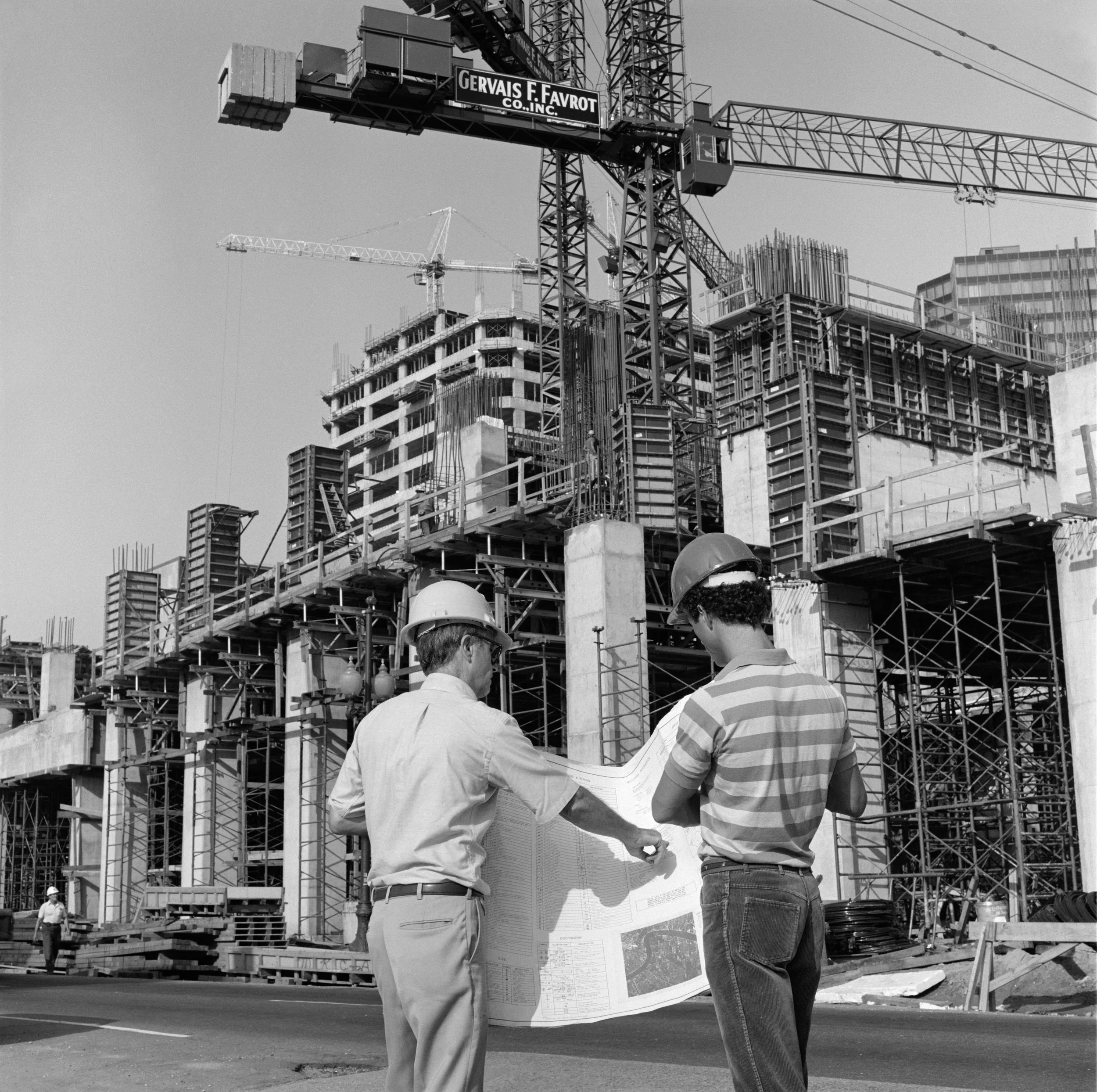 Worker using angle grinder on metal piece, wearing protective gloves and apron.