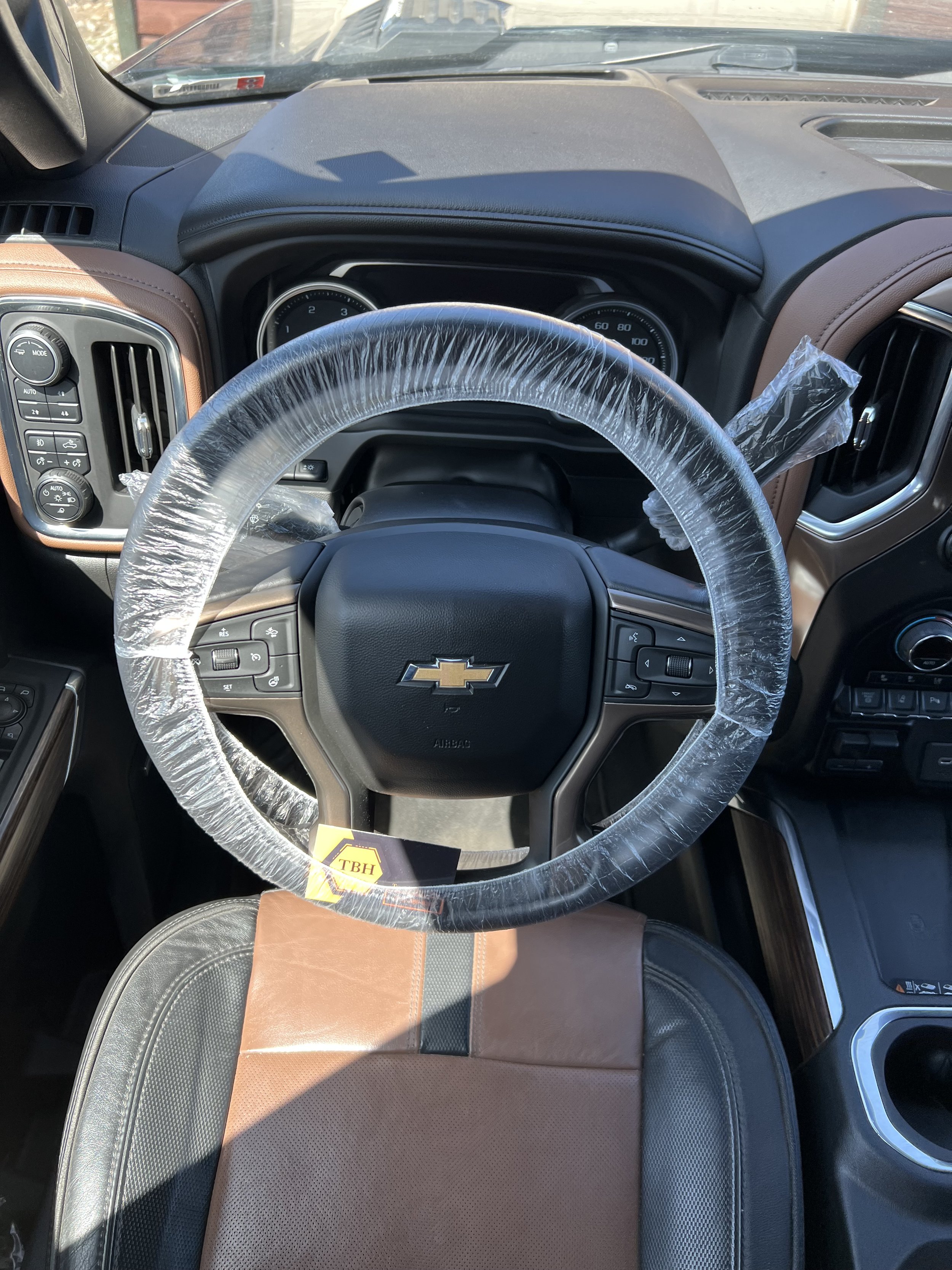 Interior of a Chevrolet vehicle showing a steering wheel covered in plastic, dashboard, and brown seat.
