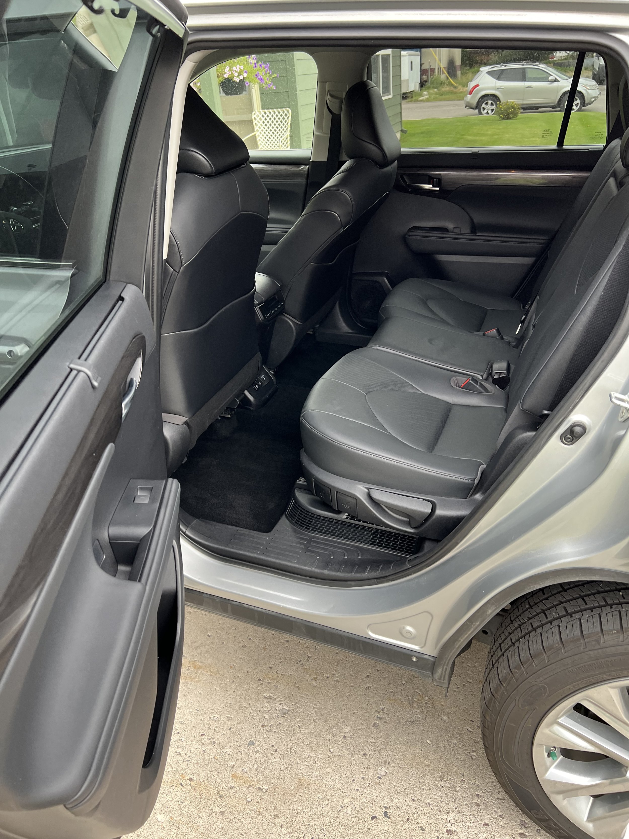 Interior view of a car's backseat with black leather upholstery and open door