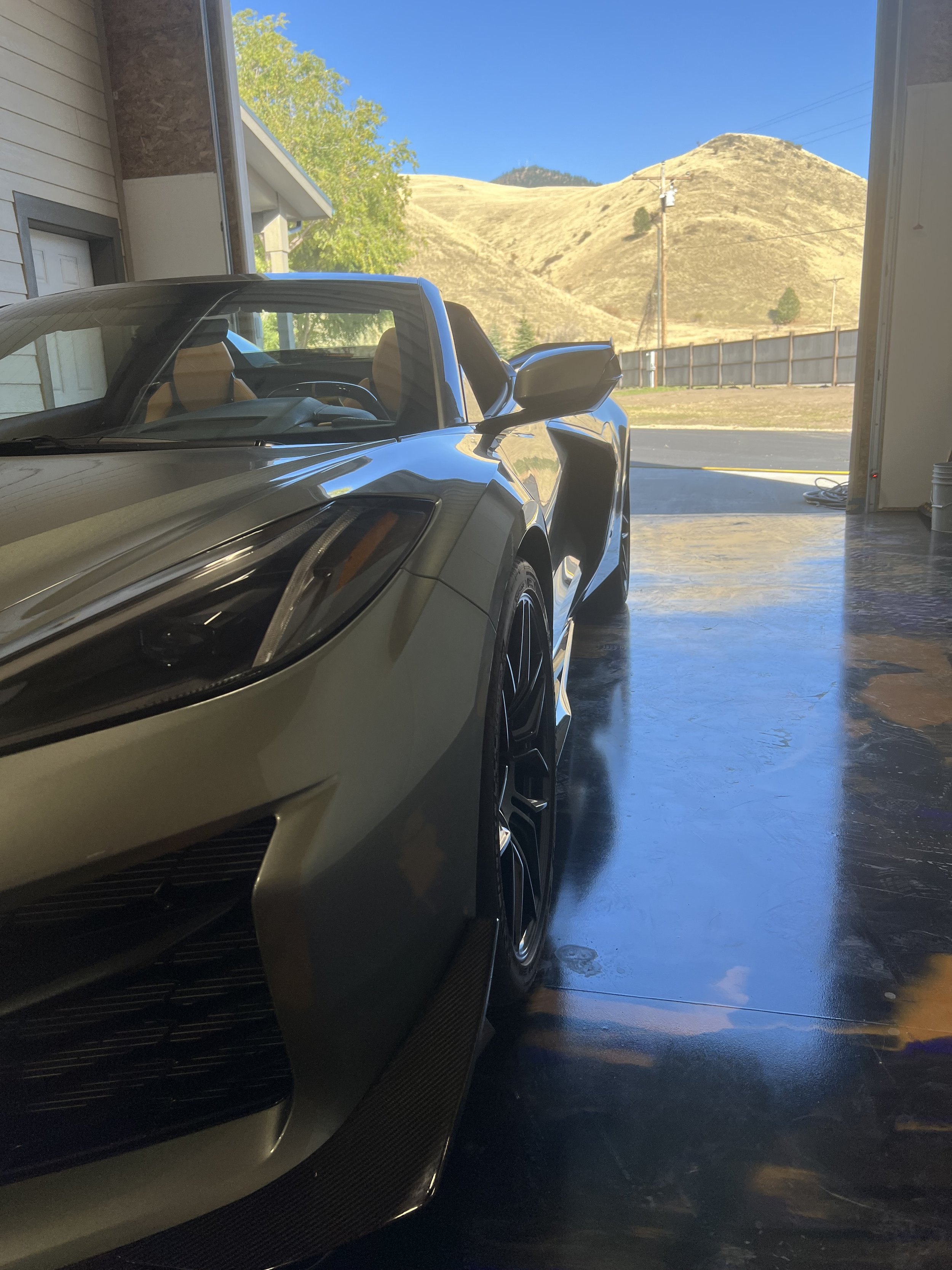Corvette sports car in a garage with mountain scenery in the background