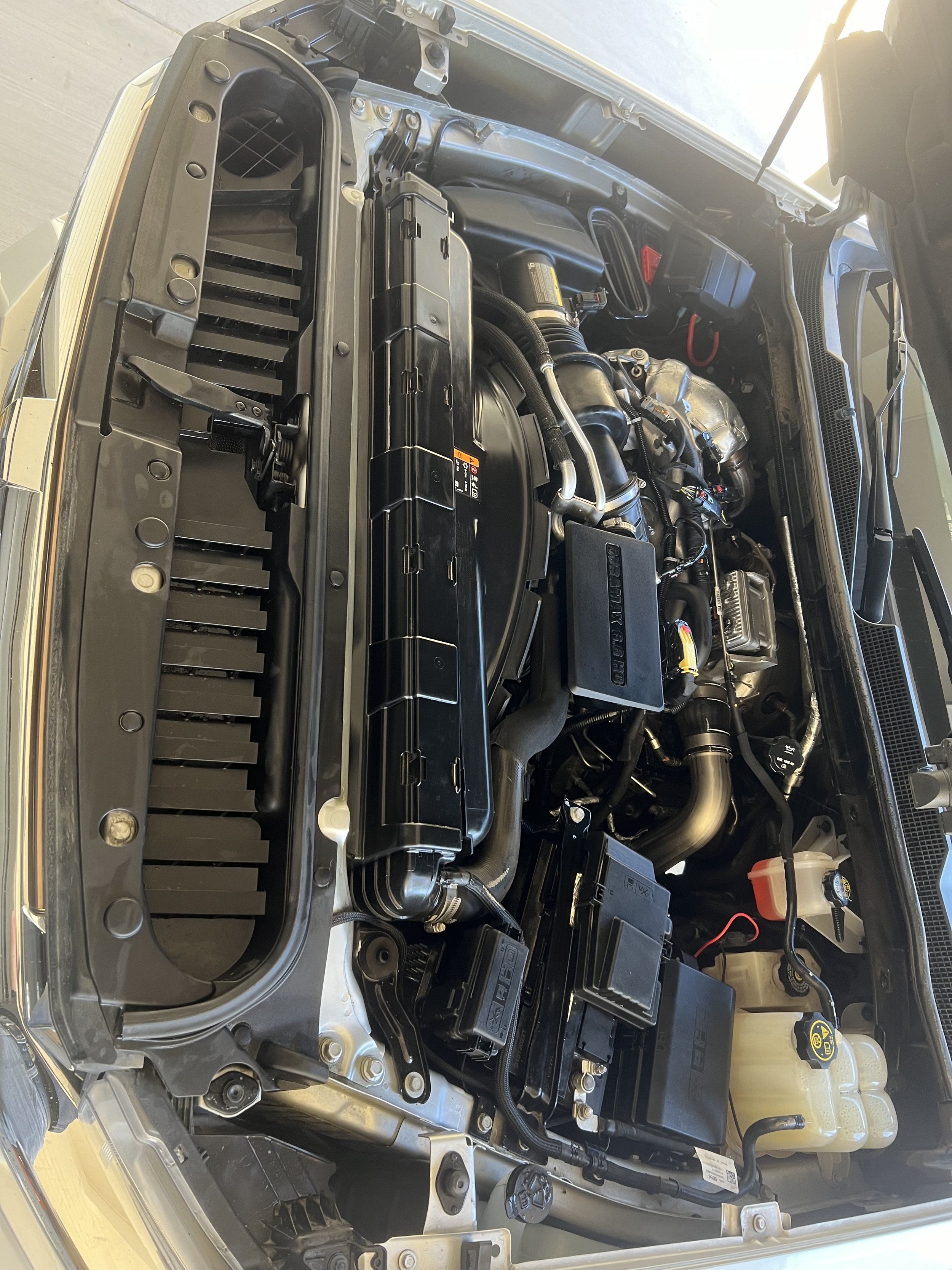 Car engine bay with visible components like radiator, air intake, and coolant reservoir.