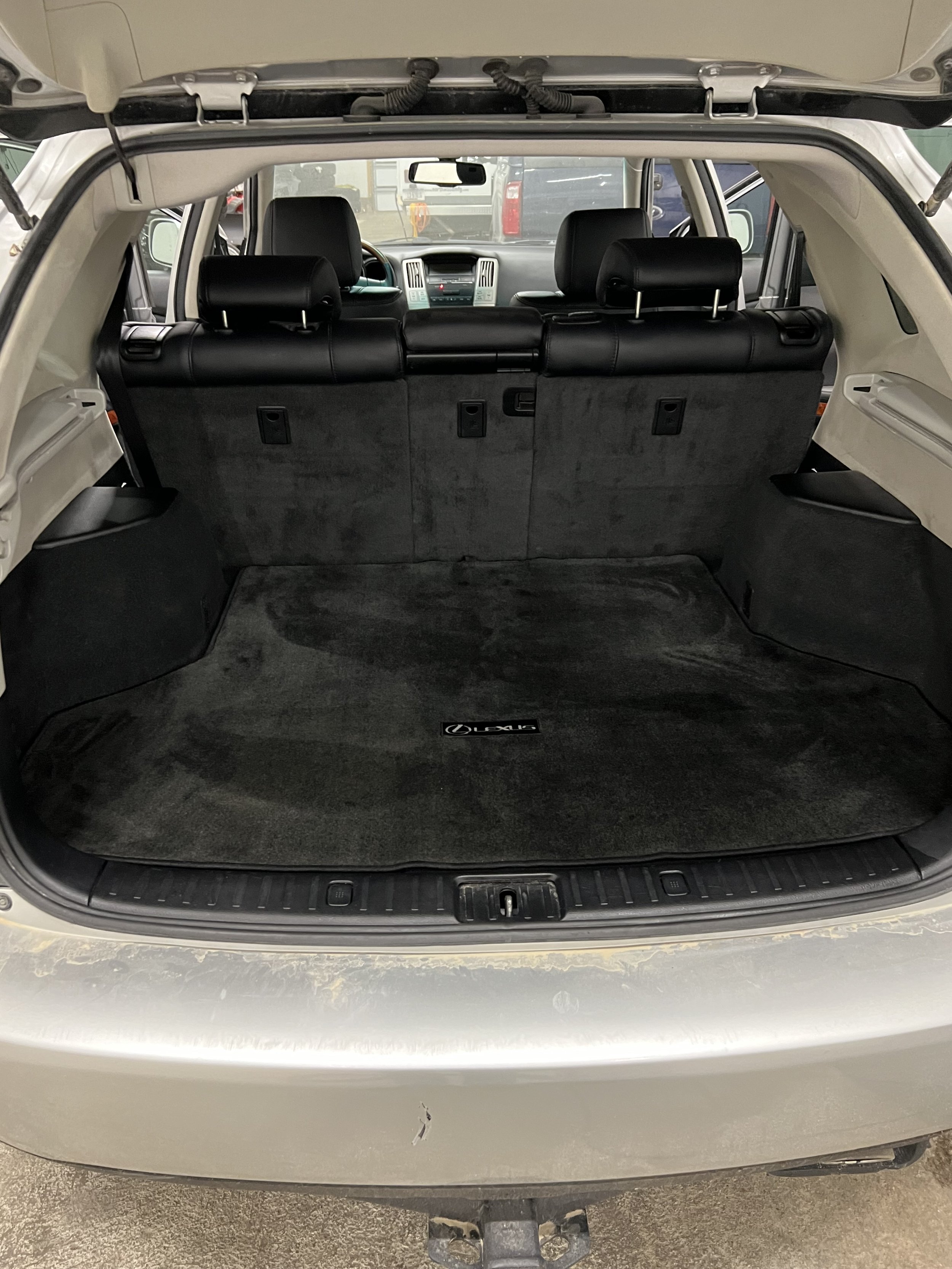 Open trunk of a Lexus SUV with black carpet and rear seats visible.