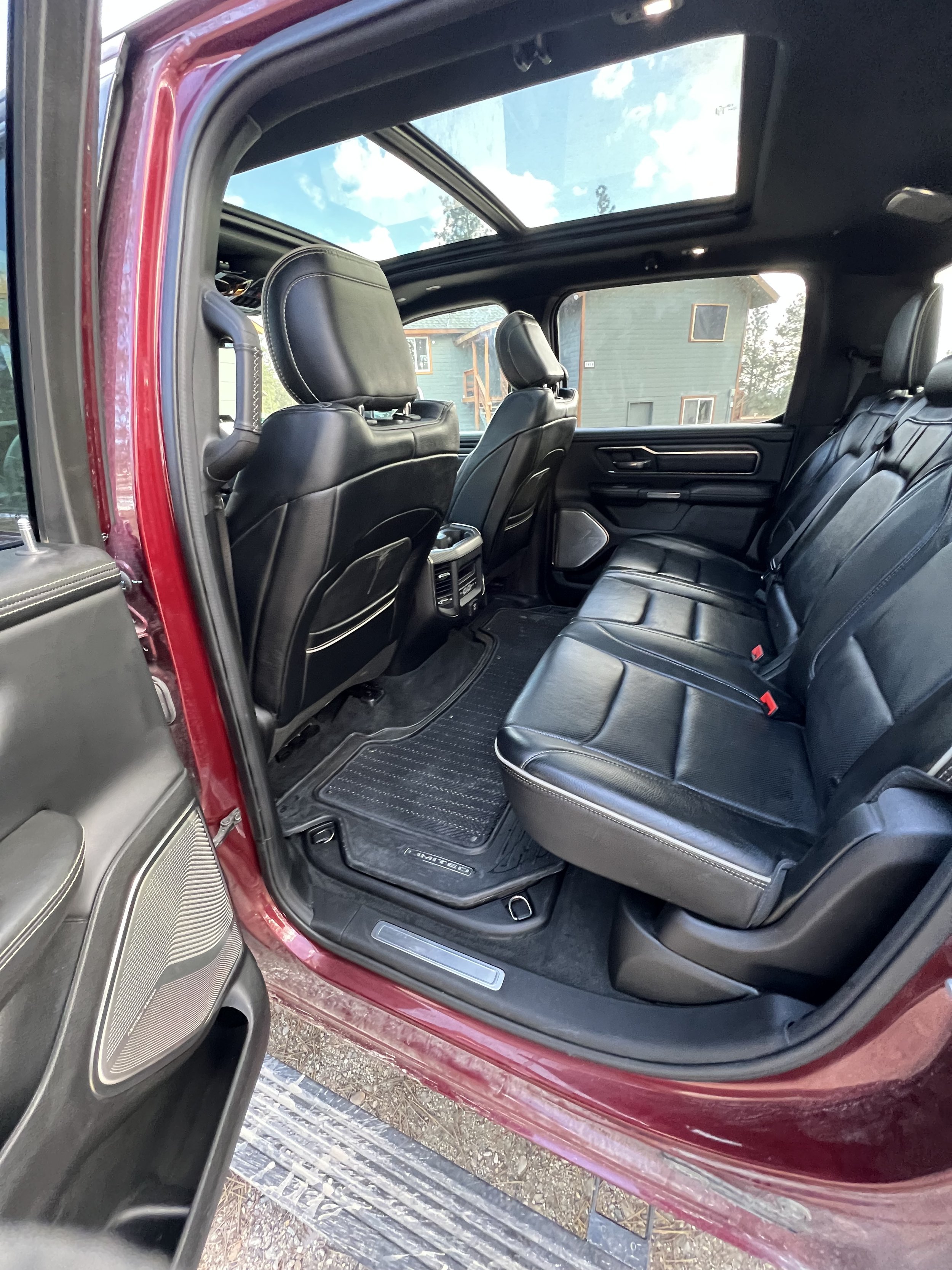 Interior of a car with black leather seats, open sunroof, and visible rubber floor mats.
