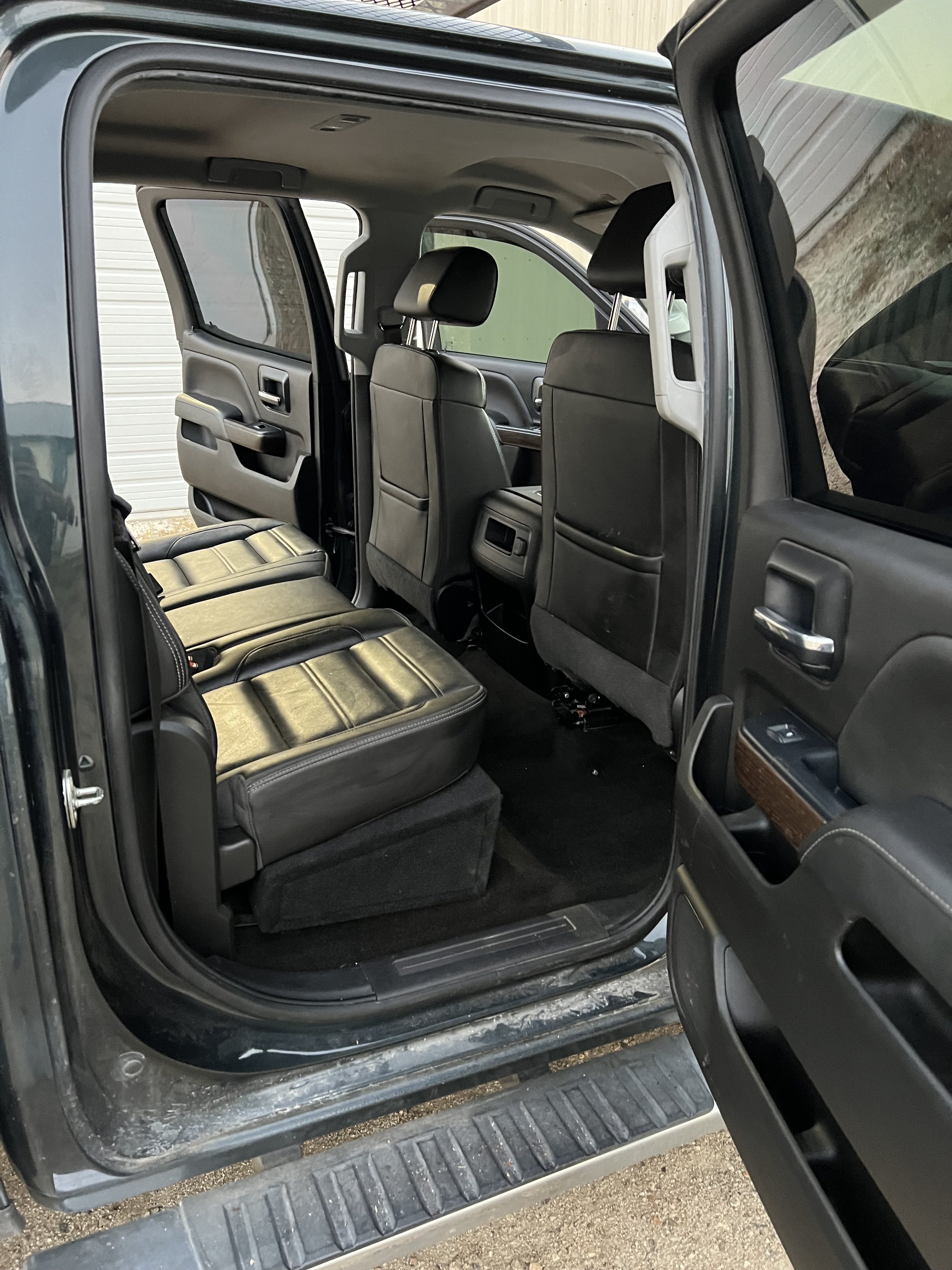 Interior of a car with open rear door showing black leather seats and interior design.