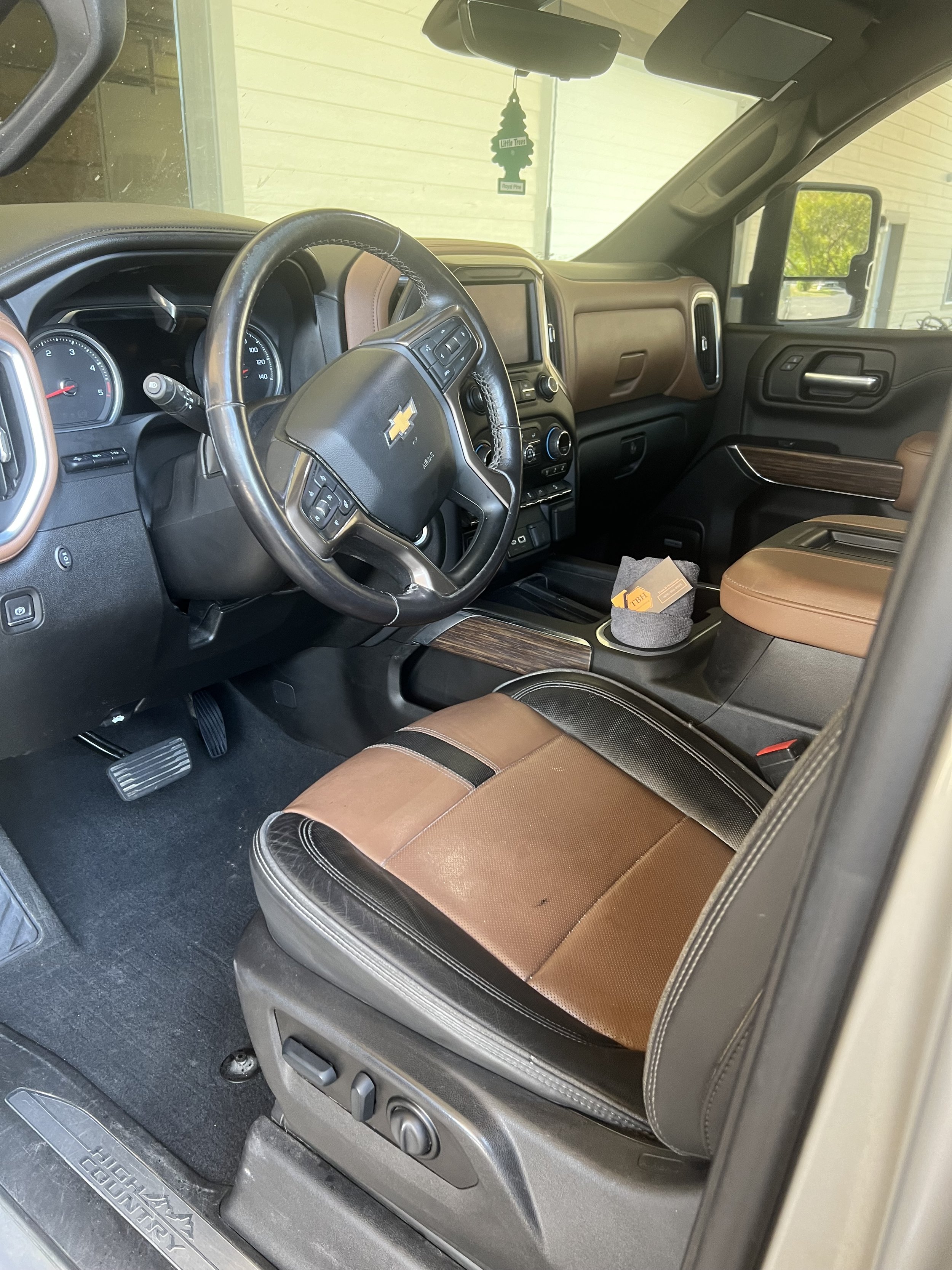 Interior of a Chevrolet truck with brown and black leather seats, dashboard, and steering wheel.