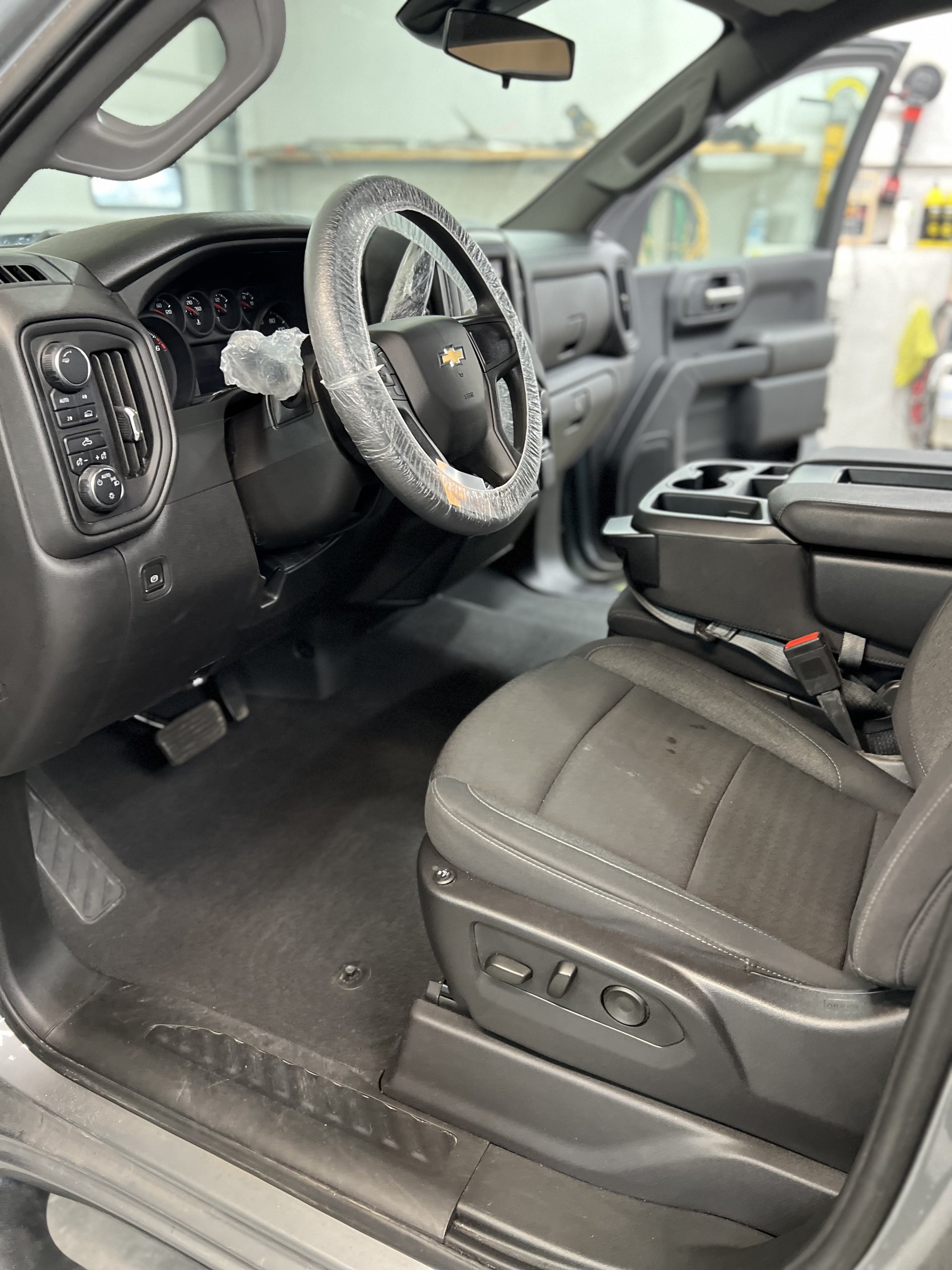 Interior of a Chevrolet vehicle with plastic-covered steering wheel and open door.