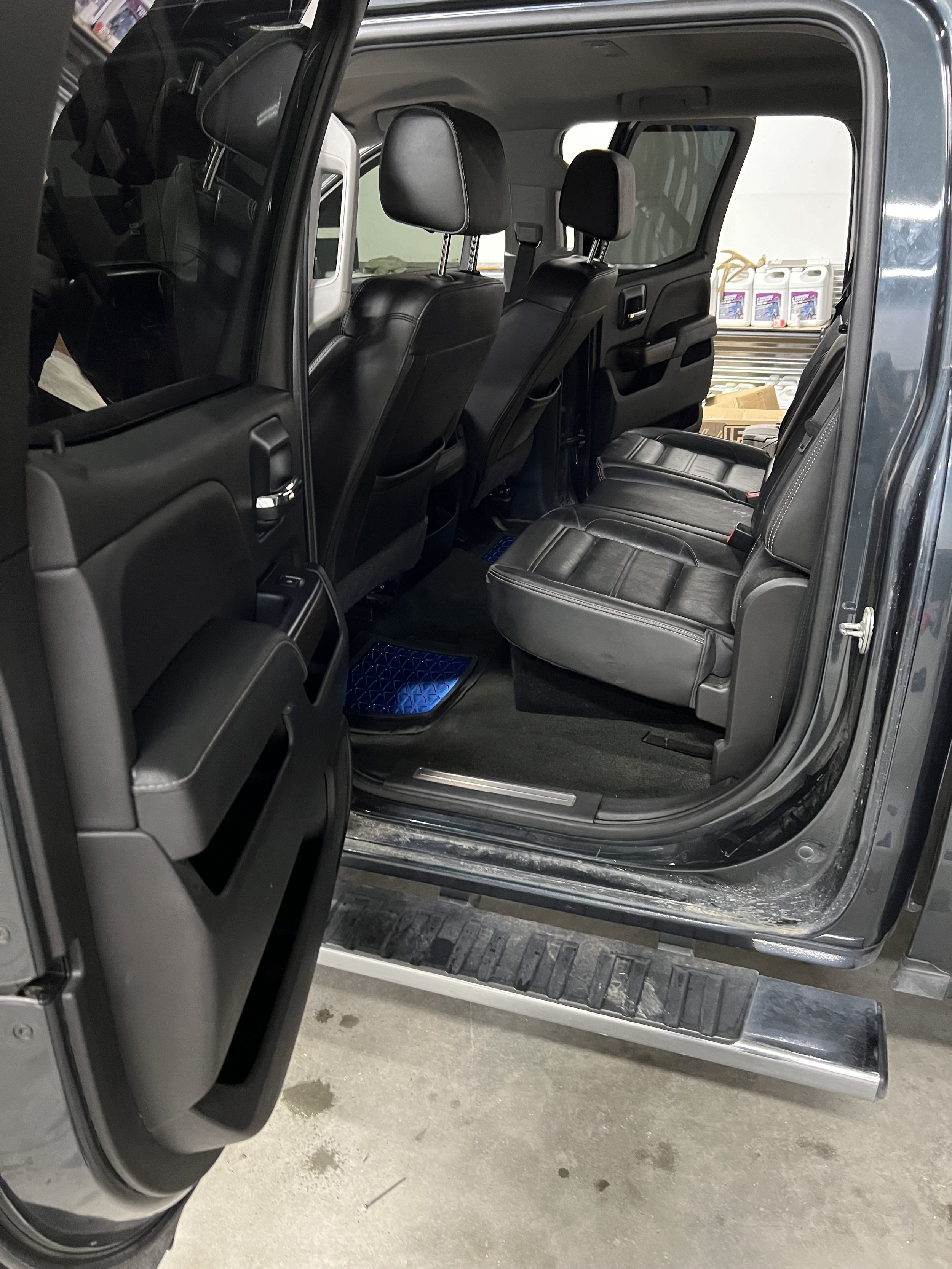 Interior view of a car's back seat with black leather seats, doors open, and visible step board, showing nearby car products.