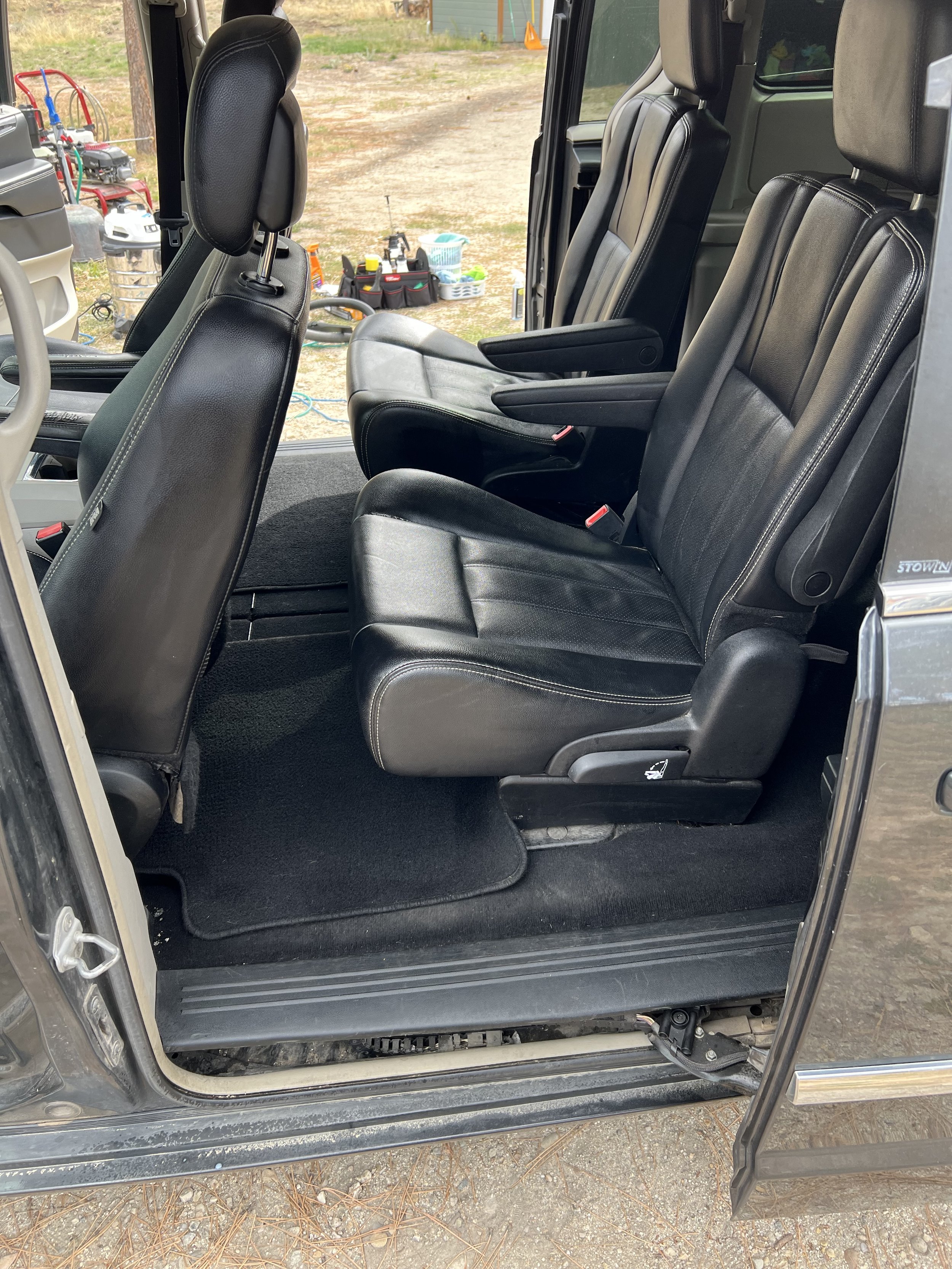 Interior of a vehicle with black leather seats and open sliding door.