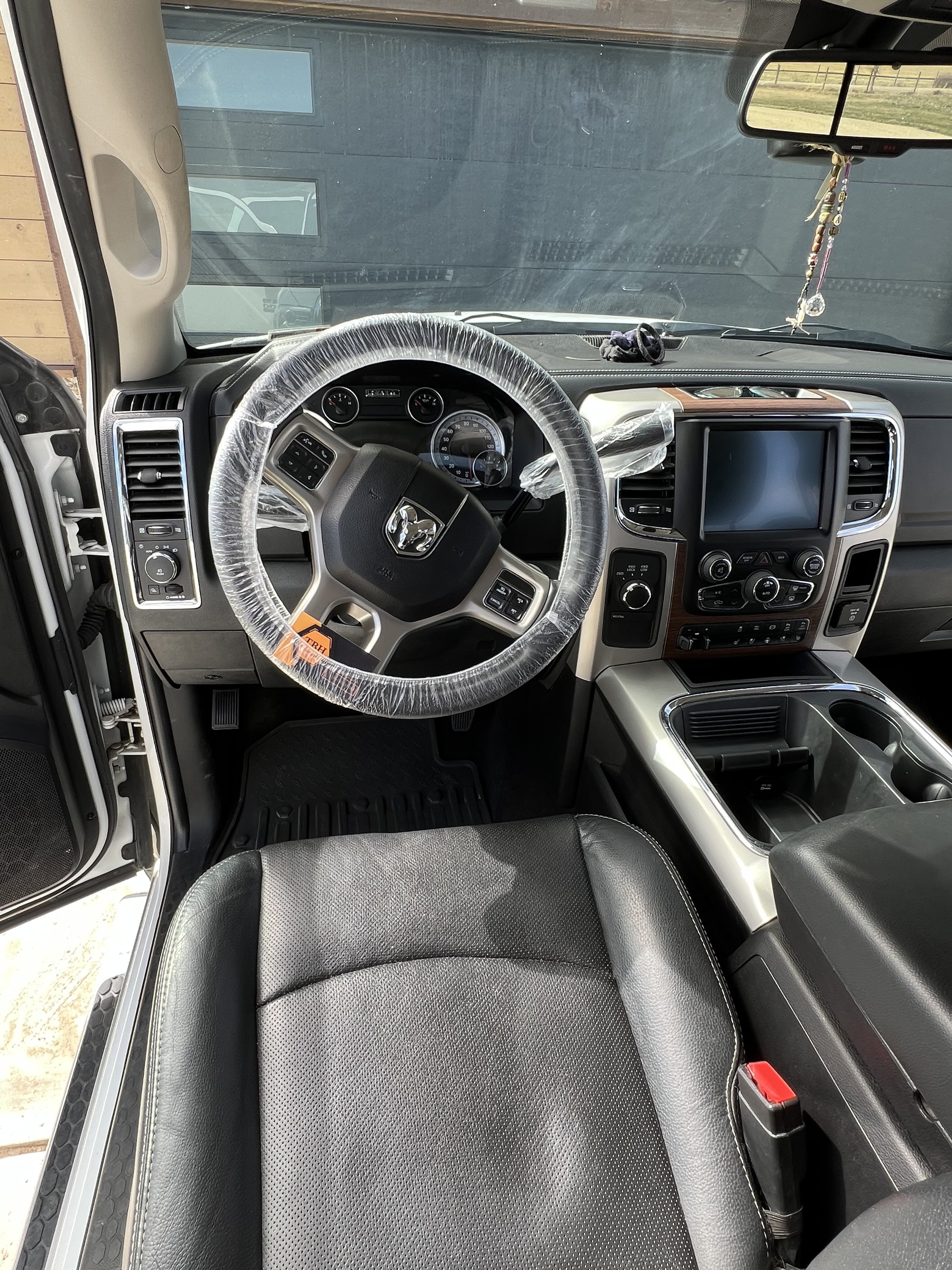 Interior of a truck with a steering wheel covered in plastic, dashboard with controls, and a touchscreen display.