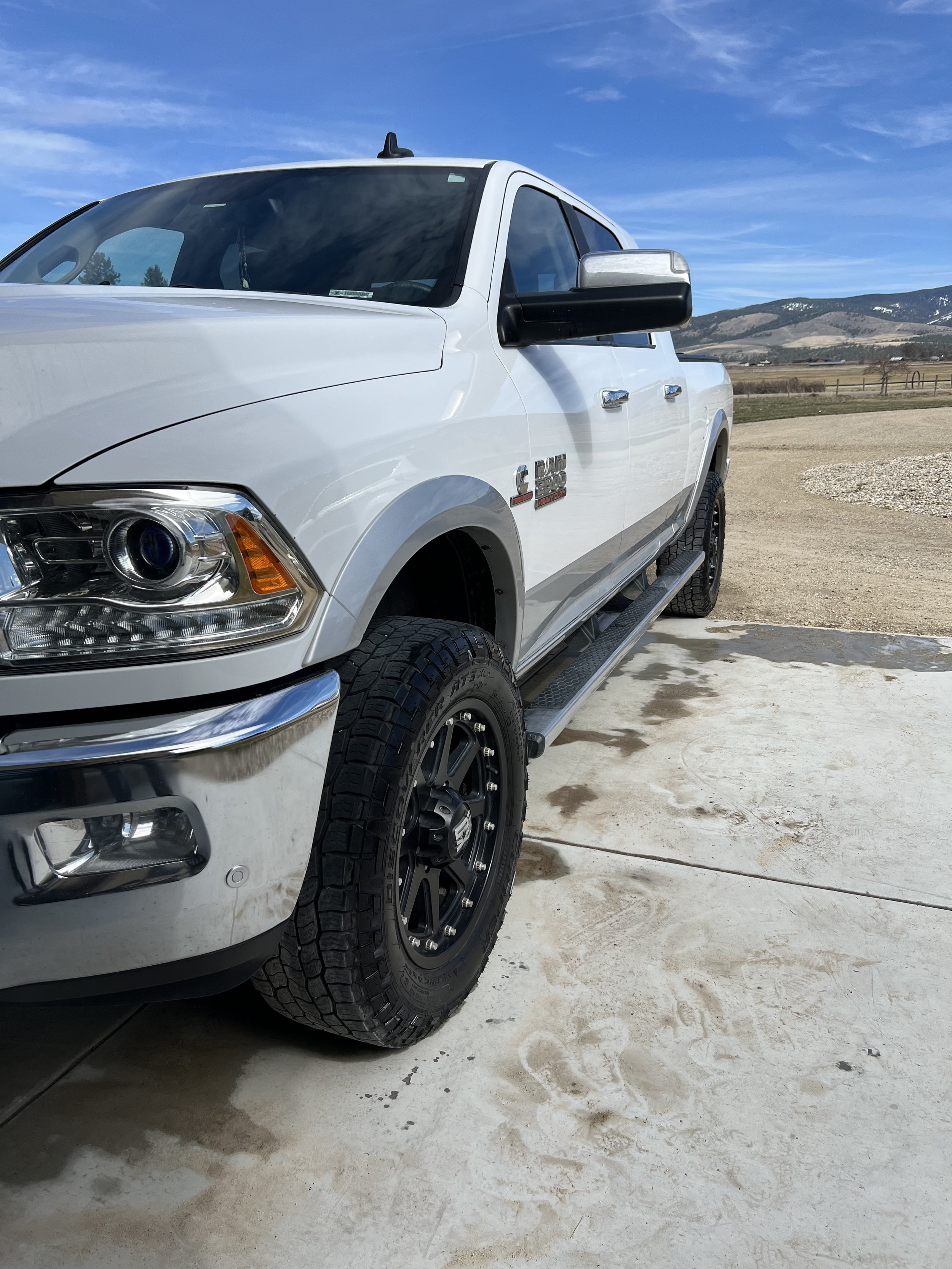 White pickup truck parked on a driveway with mountains in the background.