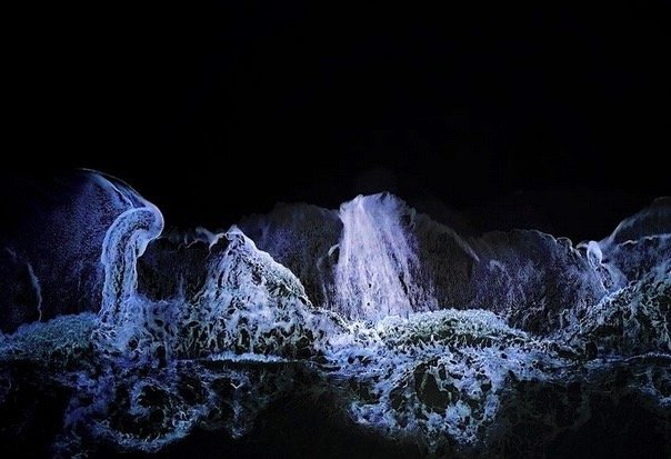 A photo of water flowing over rocks in a dark environment.