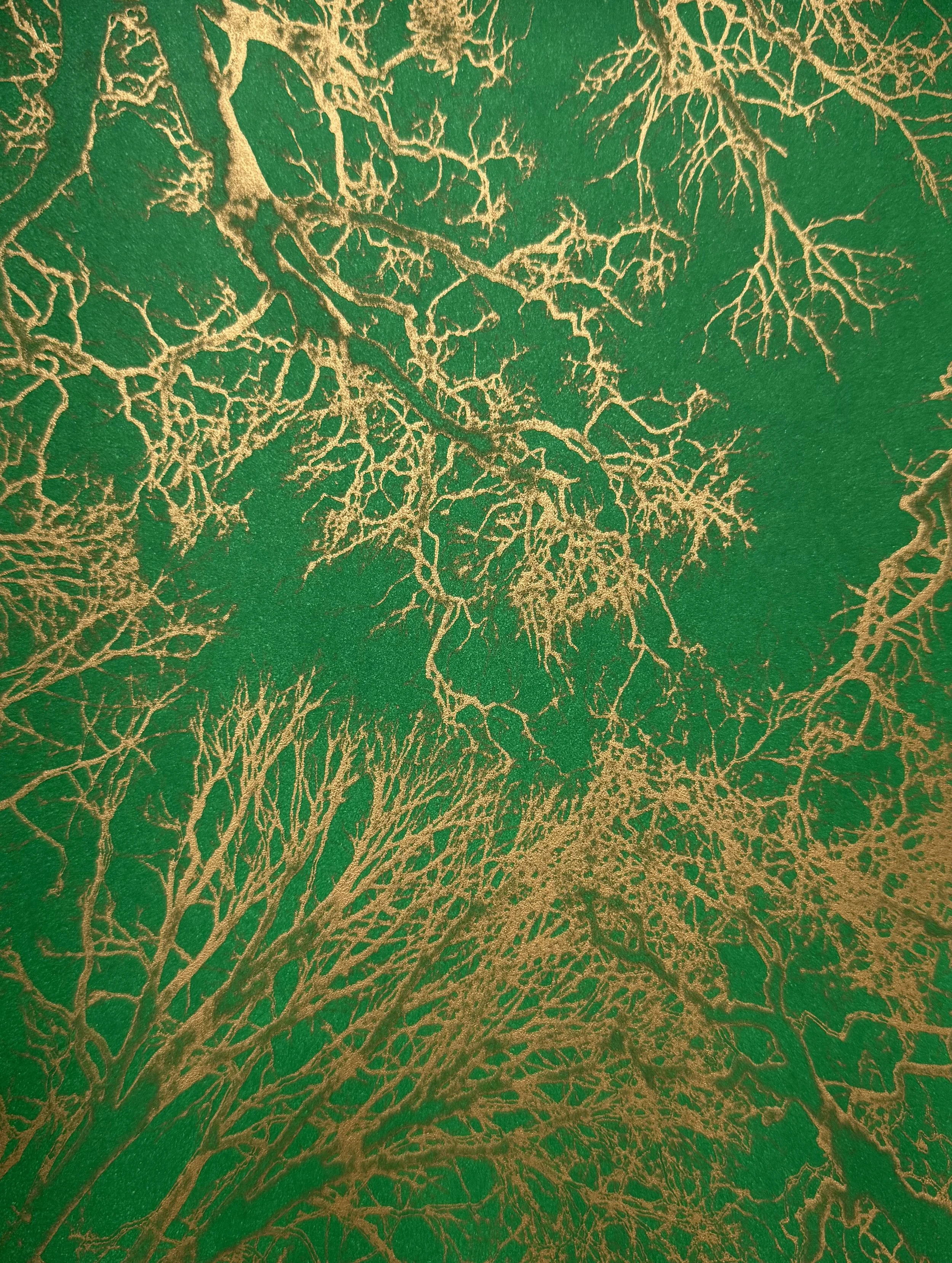 Close-up of gold-colored branches or veins on a textured green background.