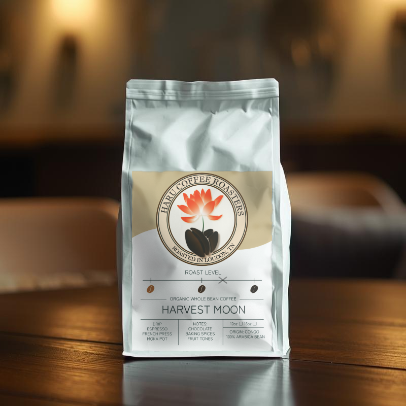 A white coffee bag with a label featuring a lotus flower and coffee beans, placed on a wooden table in a cozy, softly lit cafe.