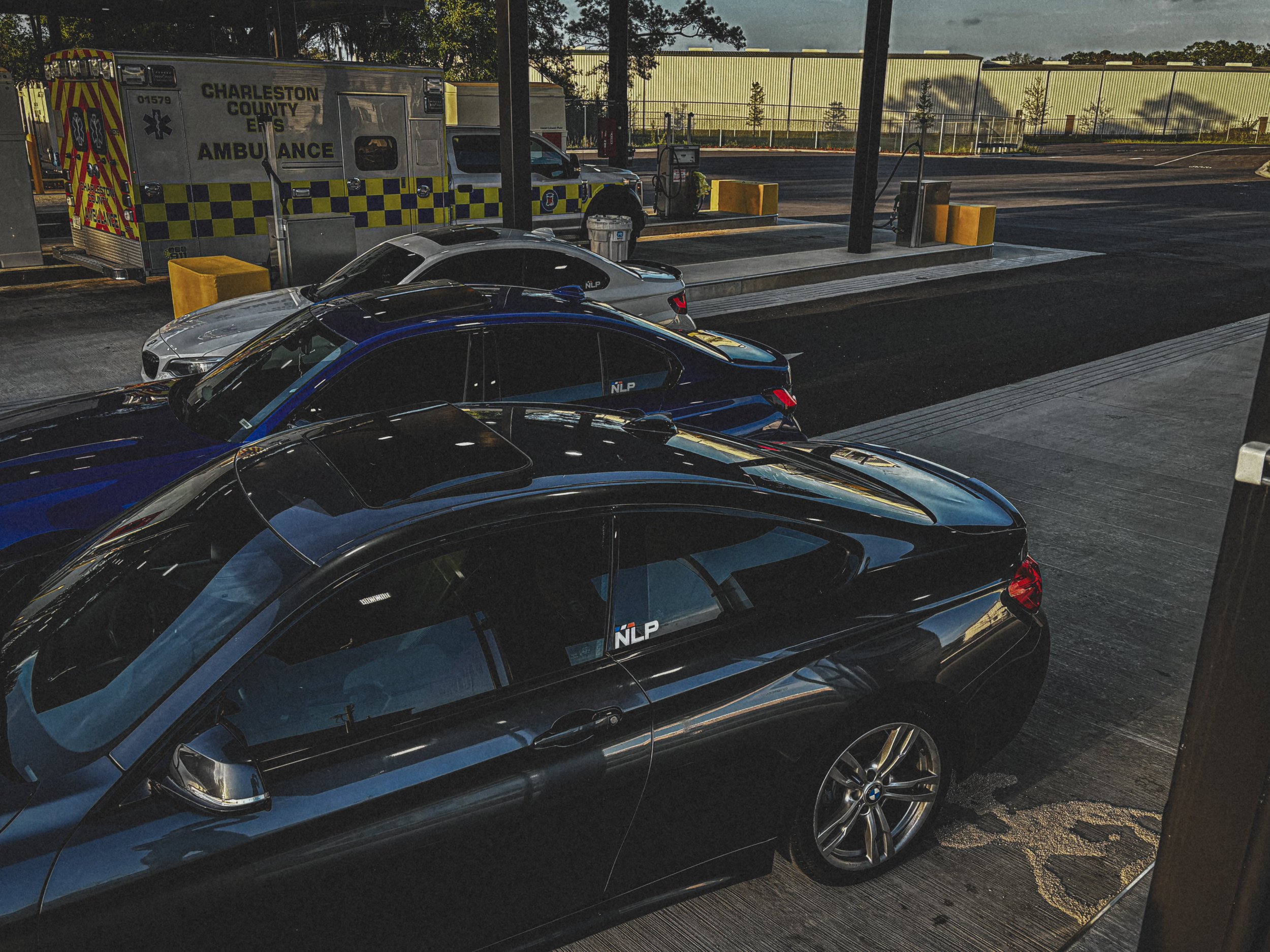 Cars parked at a gas station with a Charleston County EMS ambulance nearby.