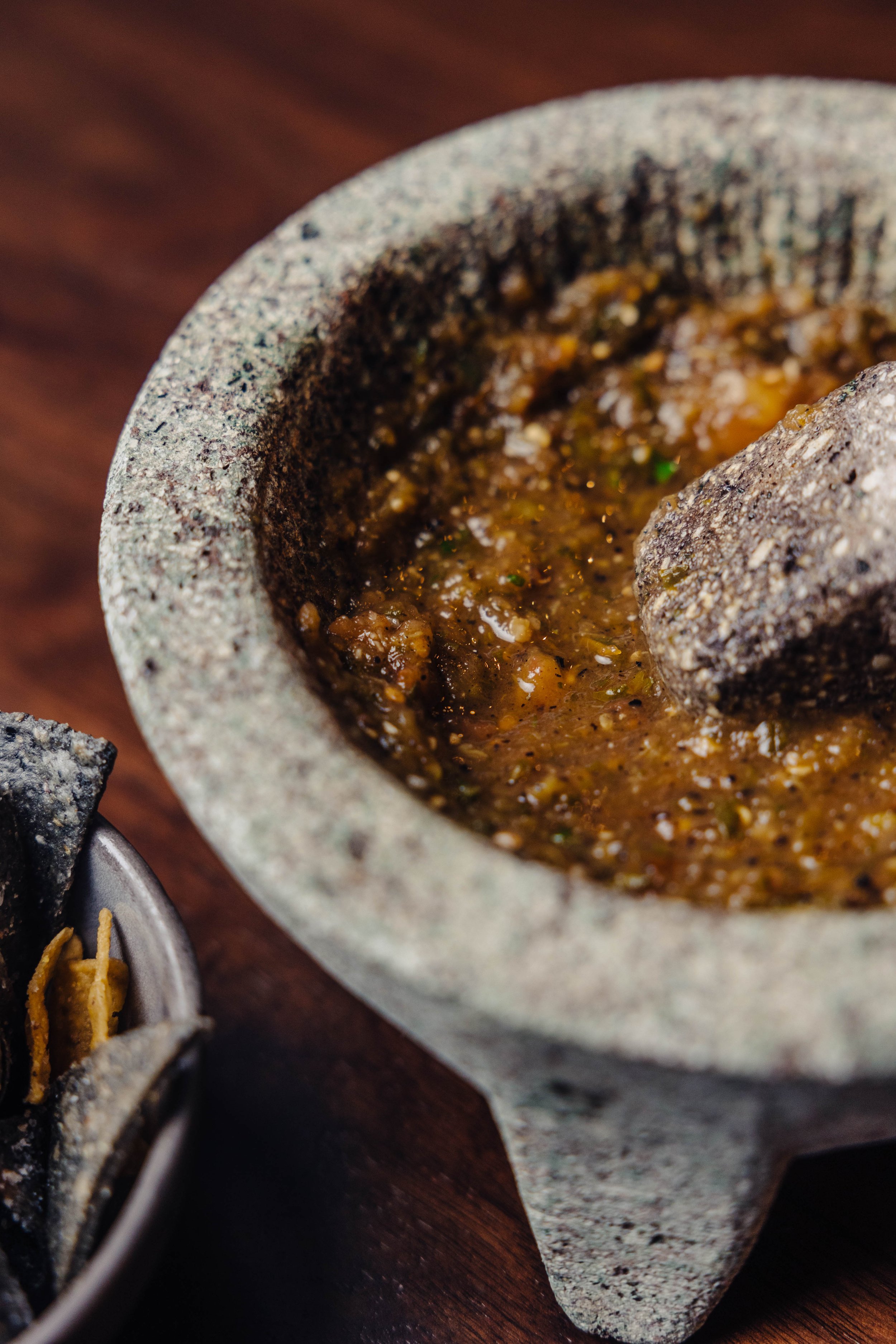 Molcajete with green salsa next to tortilla chips