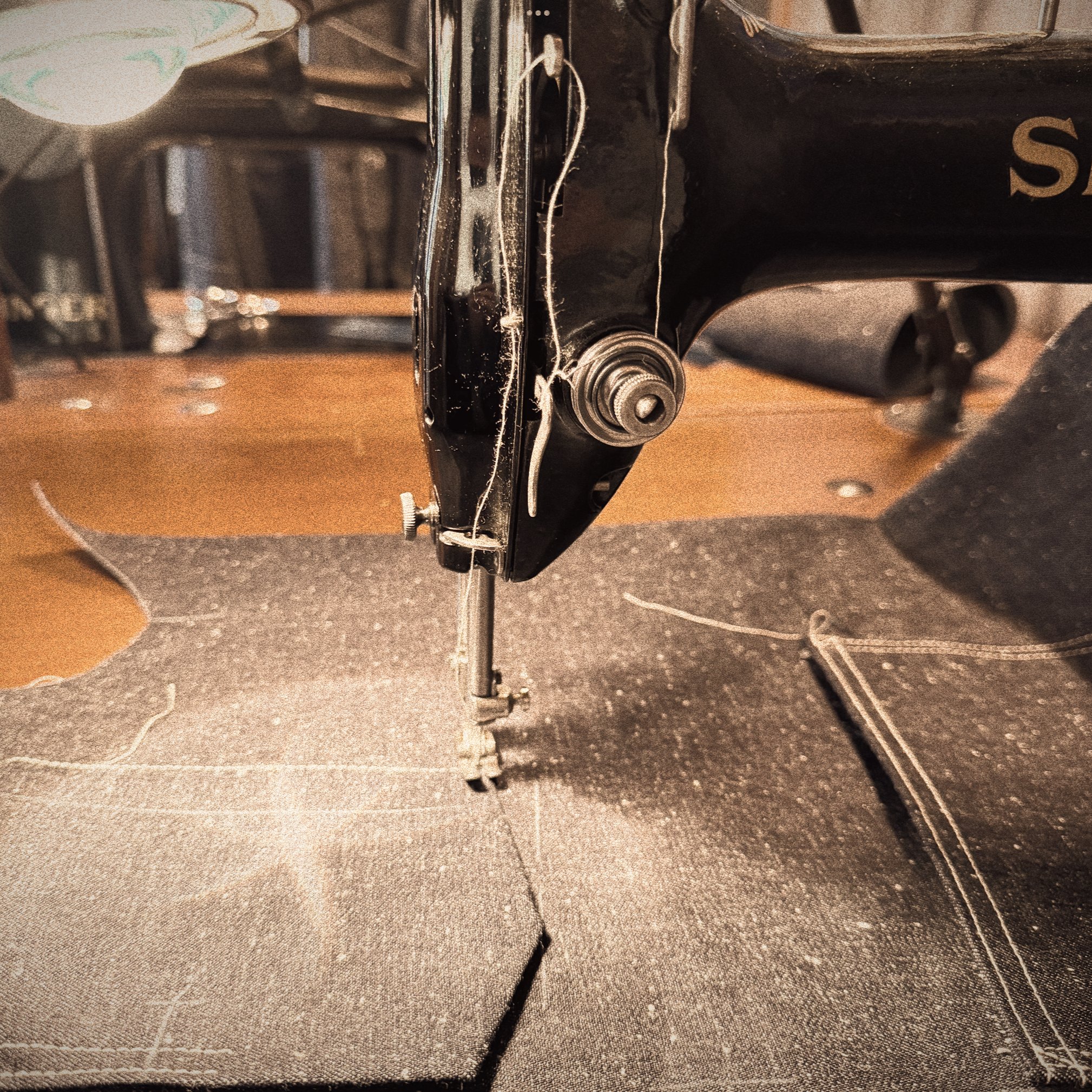 Close-up of a vintage singer sewing machine stitching denim fabric.