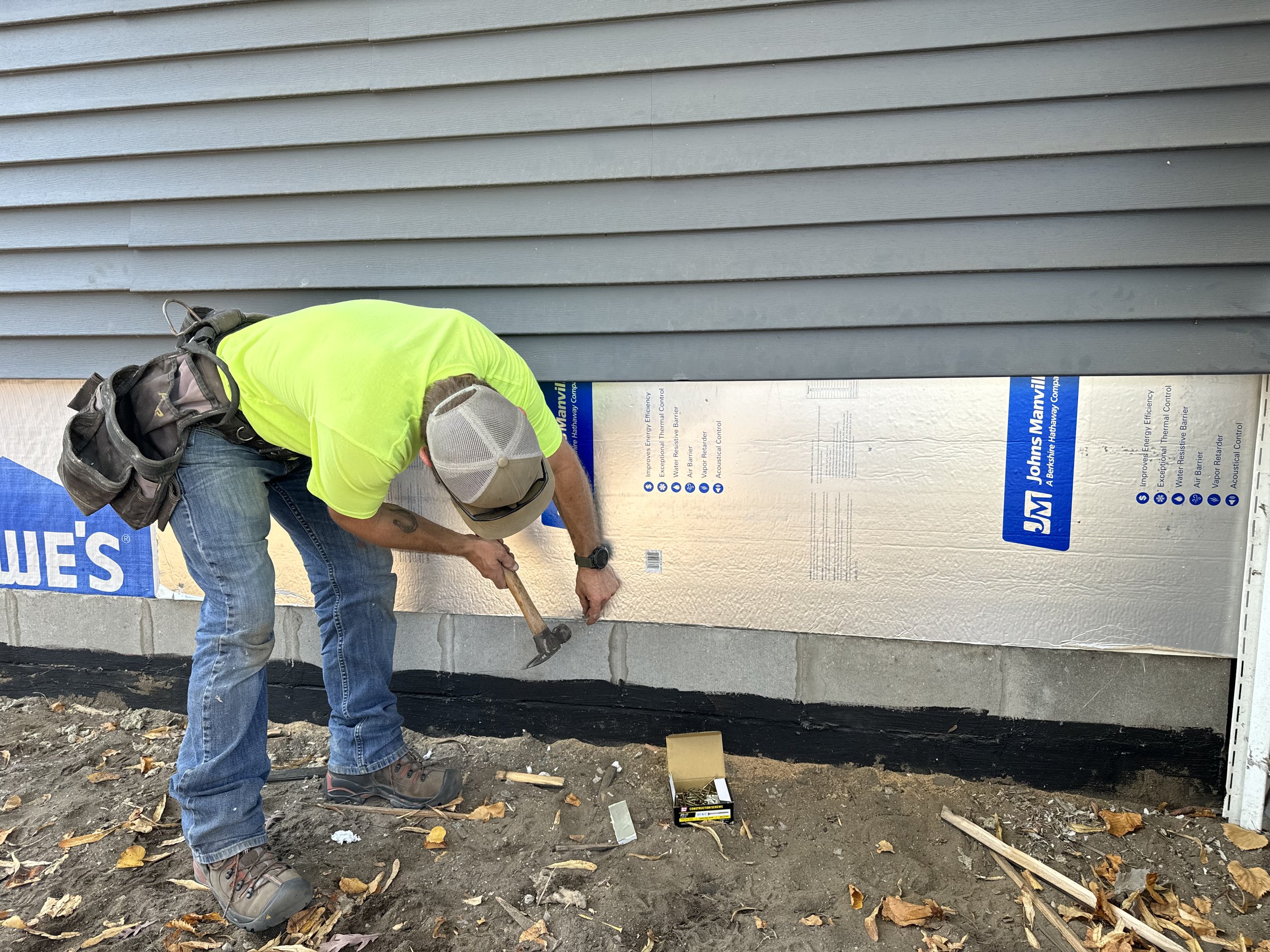 Installing exterior insulation to make up for years of waterdamaged siding.