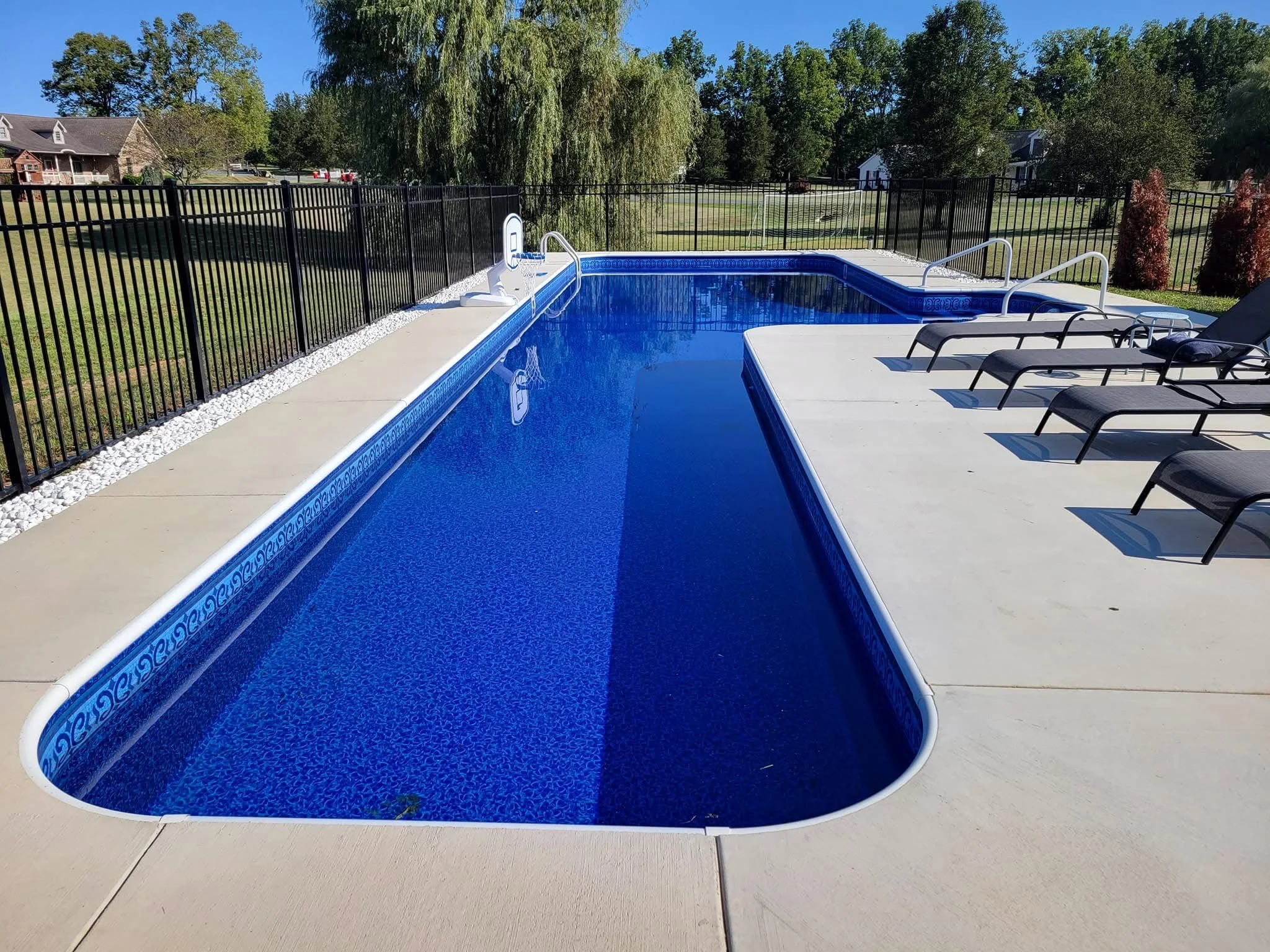 Outdoor swimming pool with lounges and black fence