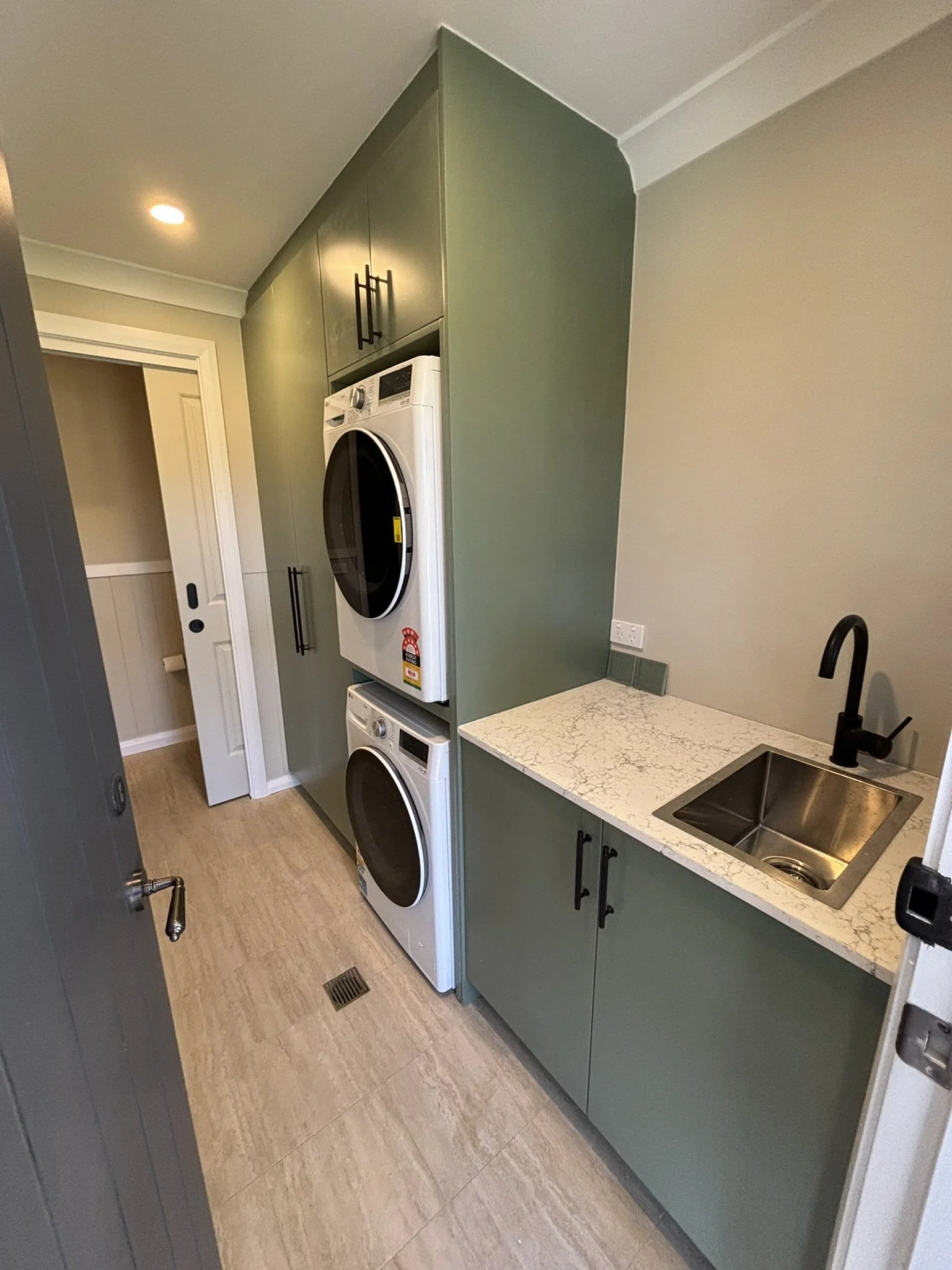 Green cabinetry and natural lighting to depict the connection from laundry interior to the Southern Highlands exterior