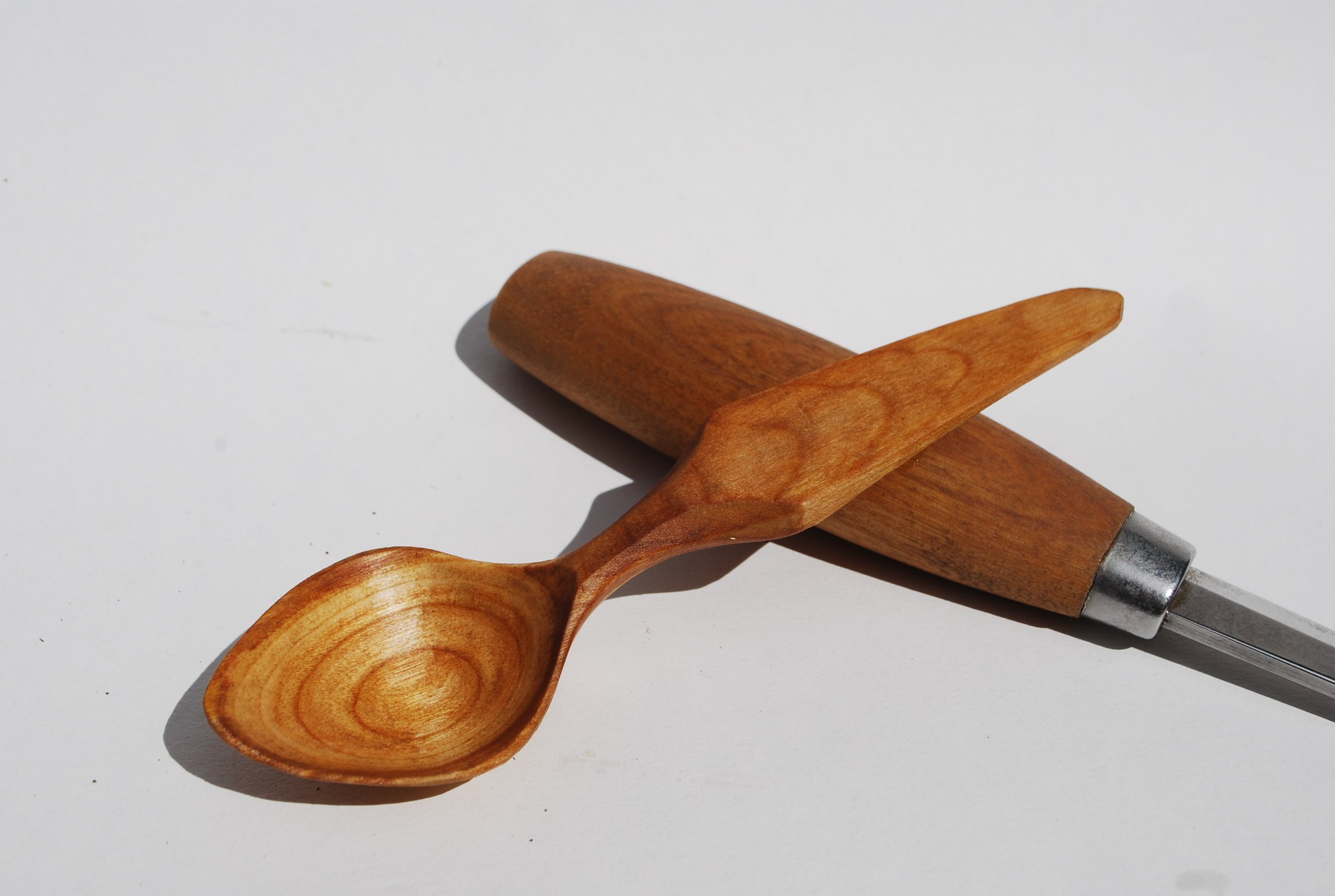 Wooden spoon and wooden rolling pin on a white surface.
