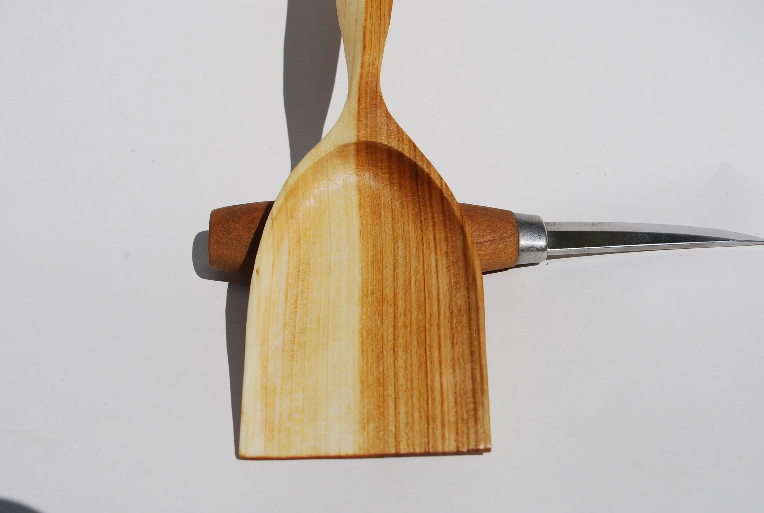 Wooden spoon, butter knife, and rolling pin arranged on a white background.